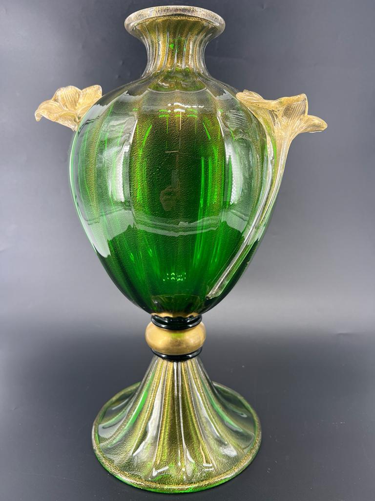 Presenting a meticulously handcrafted vase from the esteemed Eternal Glass series, this exquisite piece is an amphora resplendent in a brilliant emerald green hue. Crafted with the utmost care in Murano glass, it is adorned with intricate 24kt gold
