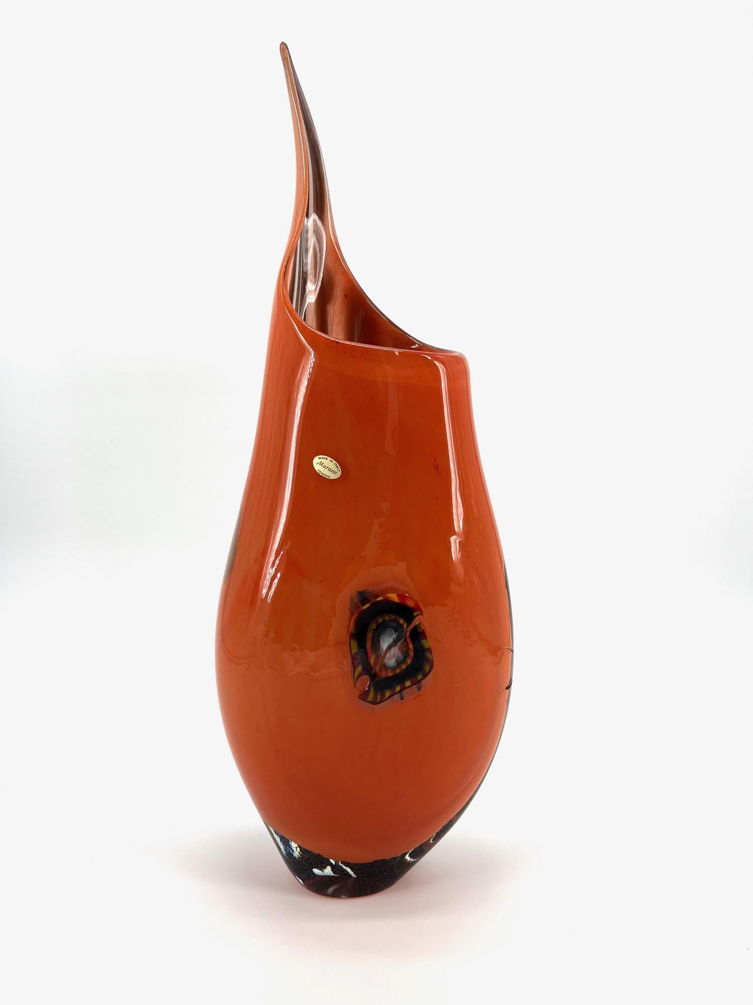 Our aim is the emotion through the creation of Murano glass artpieces.
 
This art-vase is hand made in our Murano workshop, our Master blowns a beautiful orange nouance glasses and decored with a black blown glass texture on the first side of this