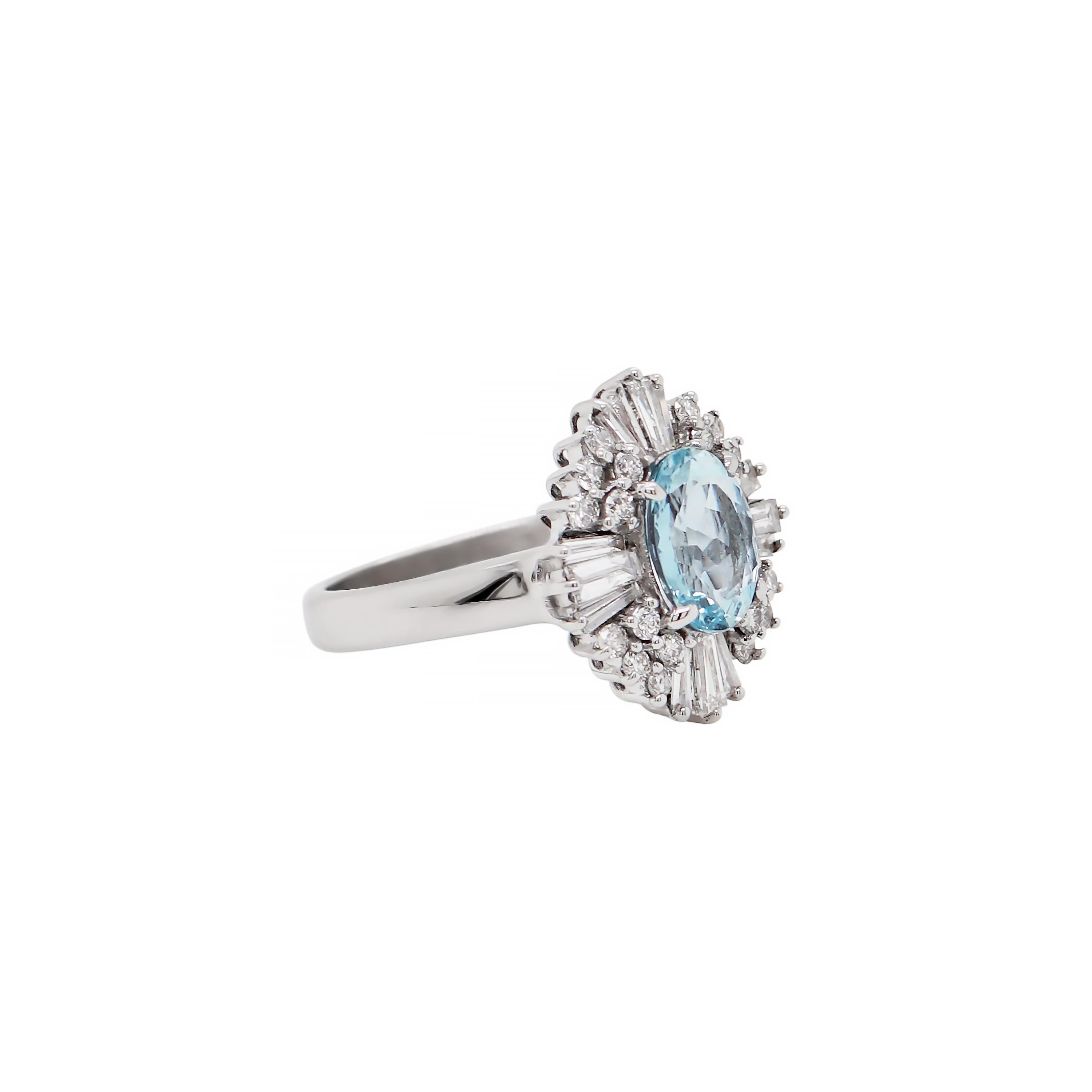 This classic ballerina cluster ring features a beautiful oval aquamarine weighing 1.29ct mounted in a four claw open back setting. The aquamarine is wonderfully surrounded by a mix of tapered banquette cut diamonds and round brilliant cut diamonds