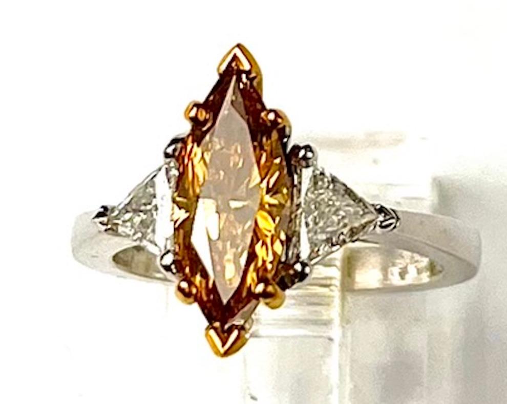 This is a simple and beautiful ring featuring an exceptionally cut  Marquise Shape Diamond that has the proportions of a 1.75Ct. and is accompanied by a GIA Report. The prominent color displayed is a deep orange yellow. It has 2 Natural White