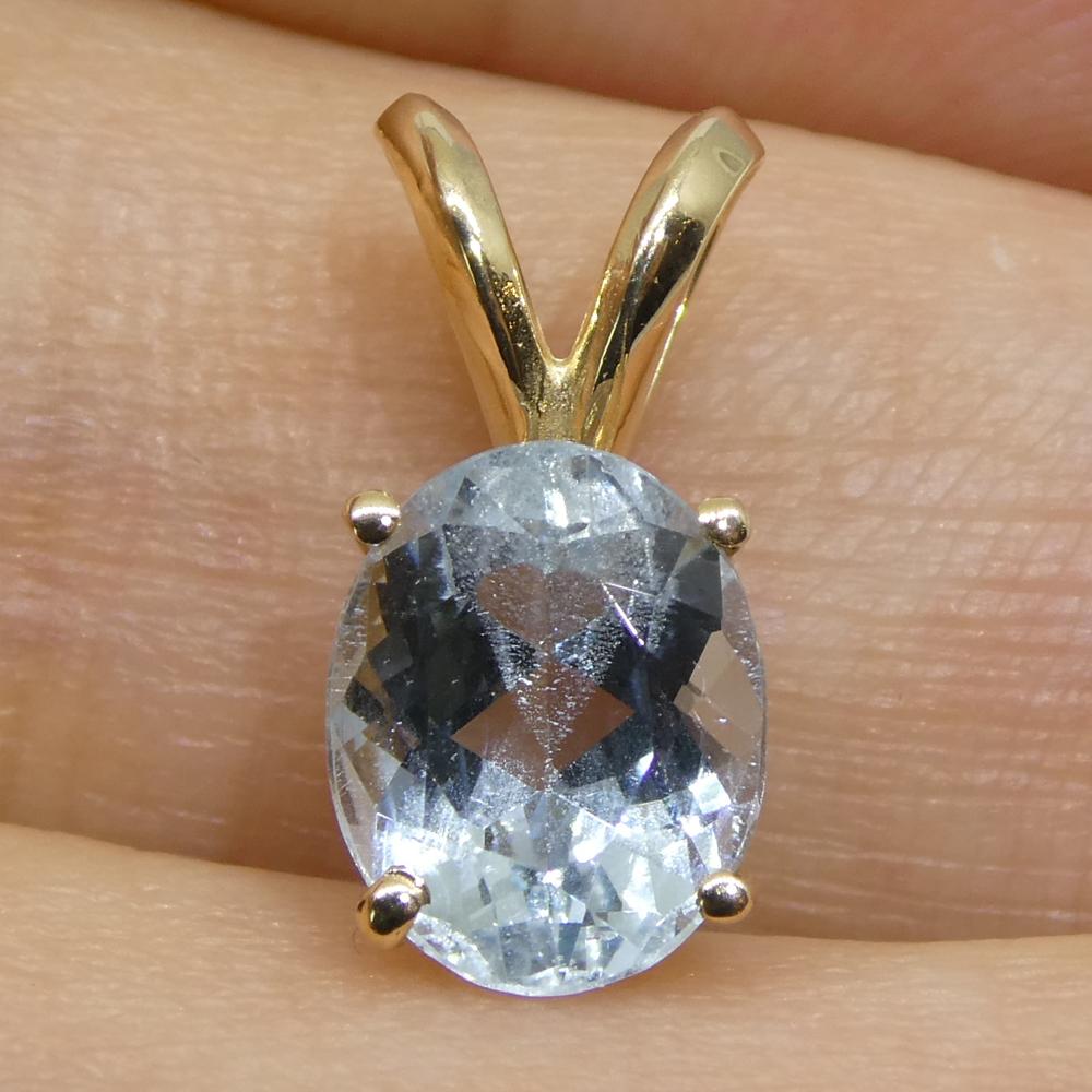 This elegant pendant showcases a 1.29-carat oval blue aquamarine set in 14k yellow gold. The aquamarine, measuring 7.98 x 6.37 x 4.45 mm, features a brilliant cut on both the crown and pavilion, enhancing its radiant sparkle. Transparent and