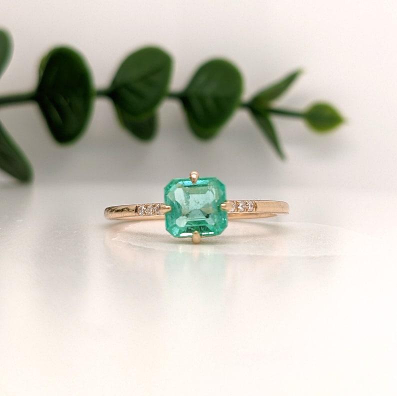 A dainty ring featuring a beautiful 1.2 carat Emerald in 14k Gold with diamond accents. A minimalist ring design perfect for an eye catching engagement or anniversary. This ring also makes a beautiful birthstone ring for your loved ones.

The