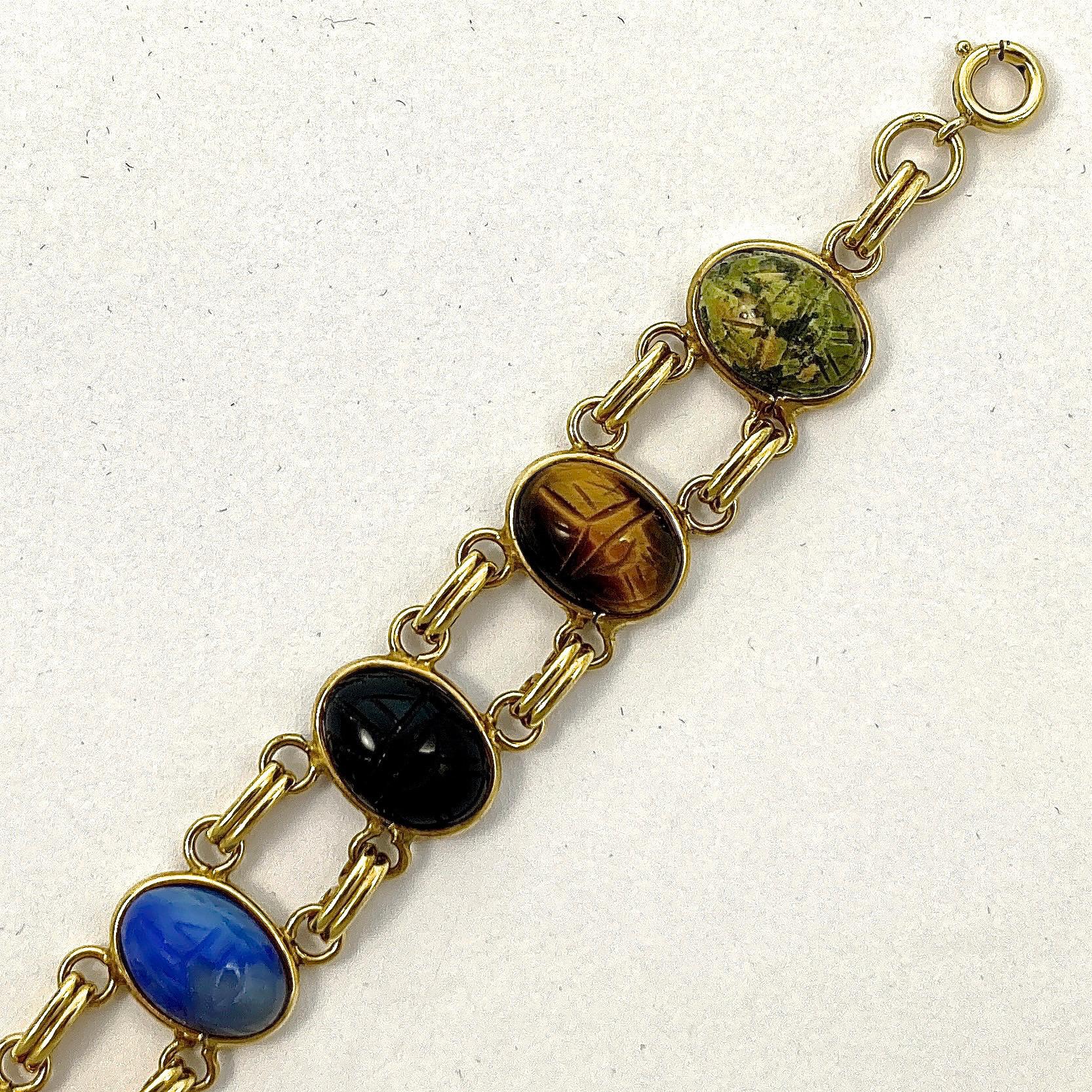 12K gold filled vintage bracelet with a safety chain, featuring engraved scarabs on semi precious stones, including tiger eye, black onyx, and carnelian. Length 17.8cm / 7 inches by width 1.45cm / .57 inch. The bracelet is in very good condition.