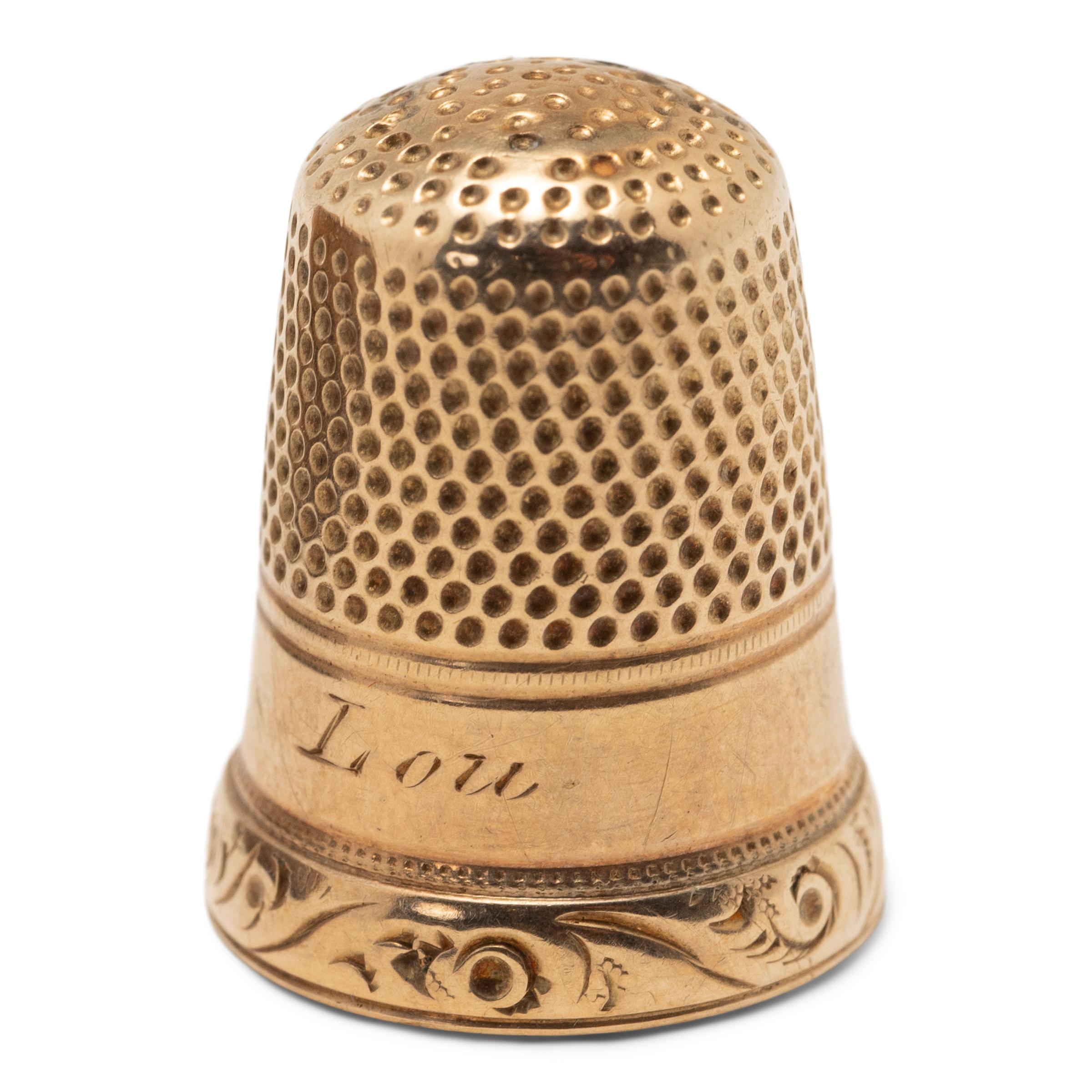 Engraved with simple and elegant scrollwork around its skirt, this European 12K gold thimble dates to the early 20th century. Cast in the late Victorian period, the thimble is engraved with the name 