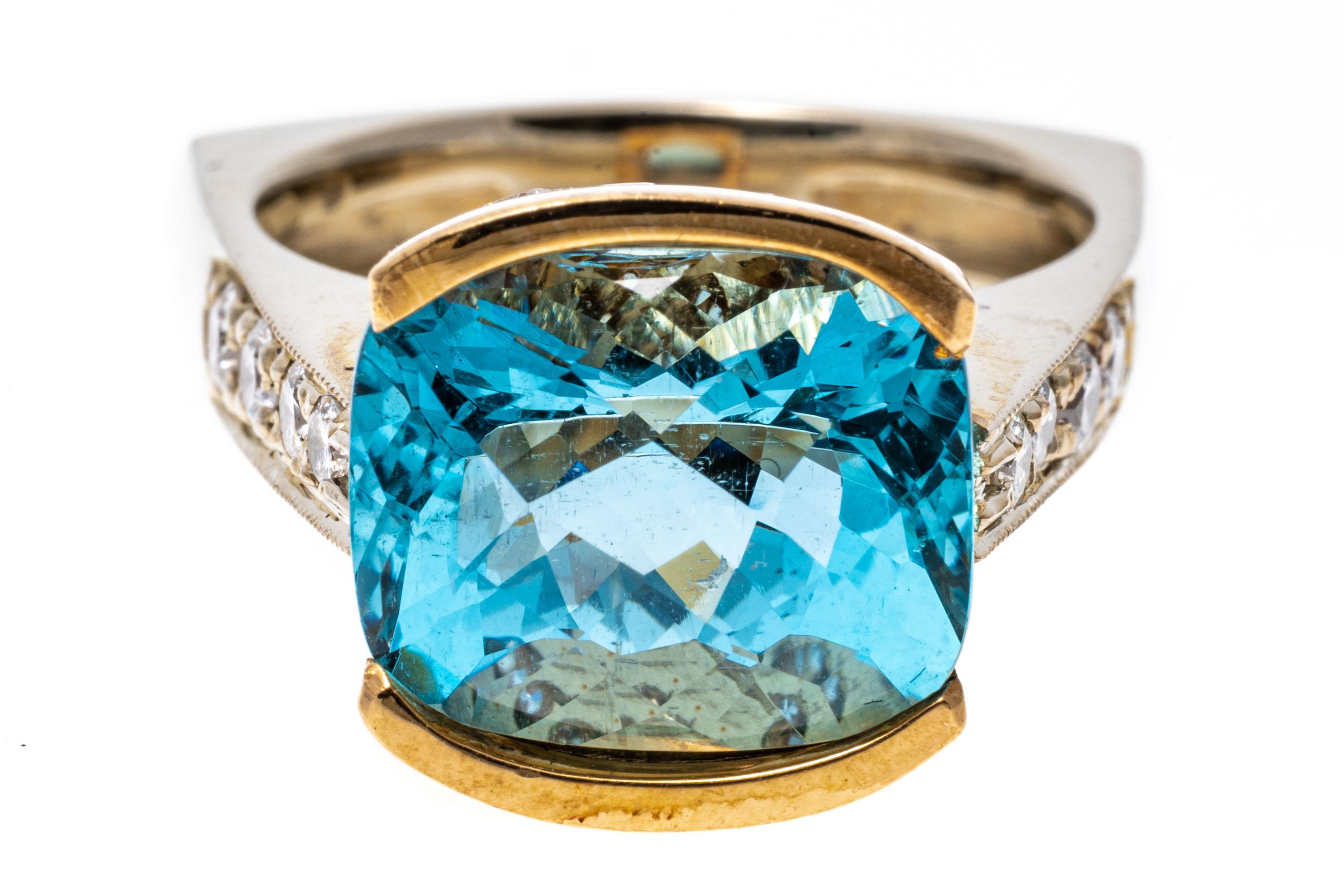 12k rose and white gold ring. This gorgeous ring has a center, checkerboard cushion faceted, medium blue color aquamarine, approximately 6.16 CTS, set in a rose gold half bezel, decorated at the bottom of the gallery with round faceted diamonds.