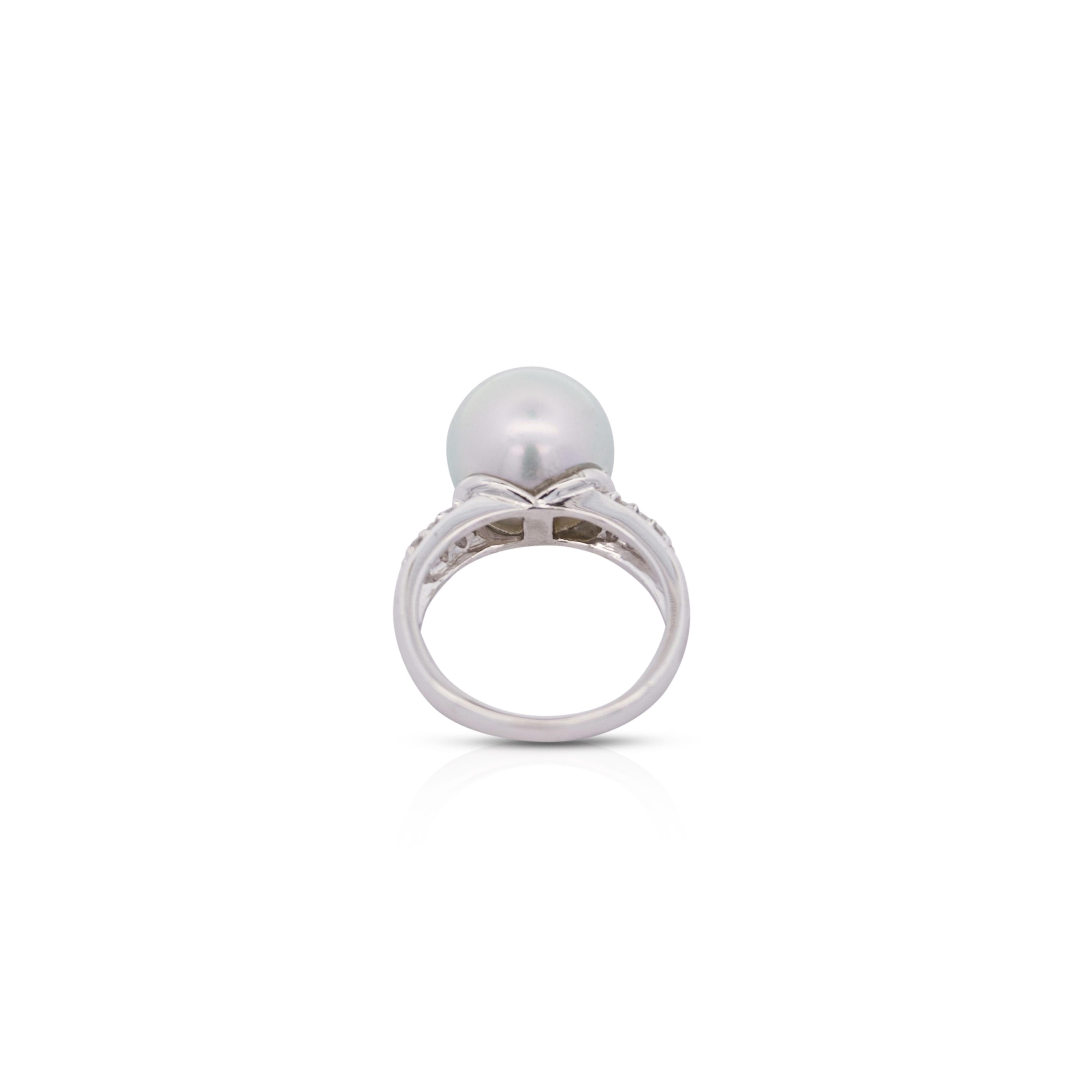 Anillo de perlas de 12 mm y diamantes de corte redondo en platino. La perla blanca brillante está engastada en bisel en el vástago del anillo de estilo tradicional, y a cada lado de la perla aparecen 6 piedras laterales de diamante de talla redonda