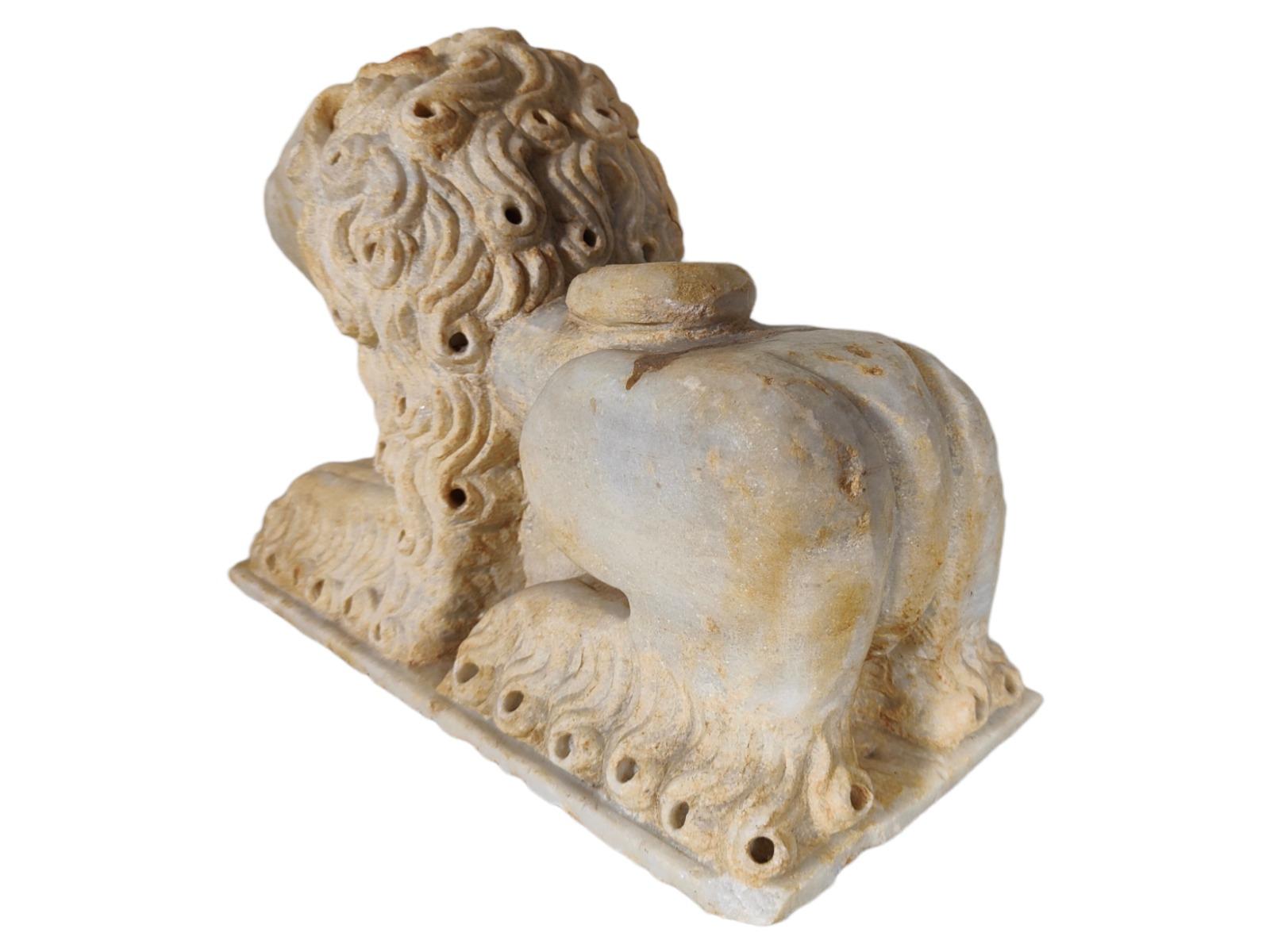 Lion couché en marbre de style roman italien du 12e siècle
Lion en marbre romain italien du 12e siècle 

La crinière et la queue stylisées s'enroulent autour du corps et des hanches, les pattes avant sont légèrement fléchies et reposent sur une