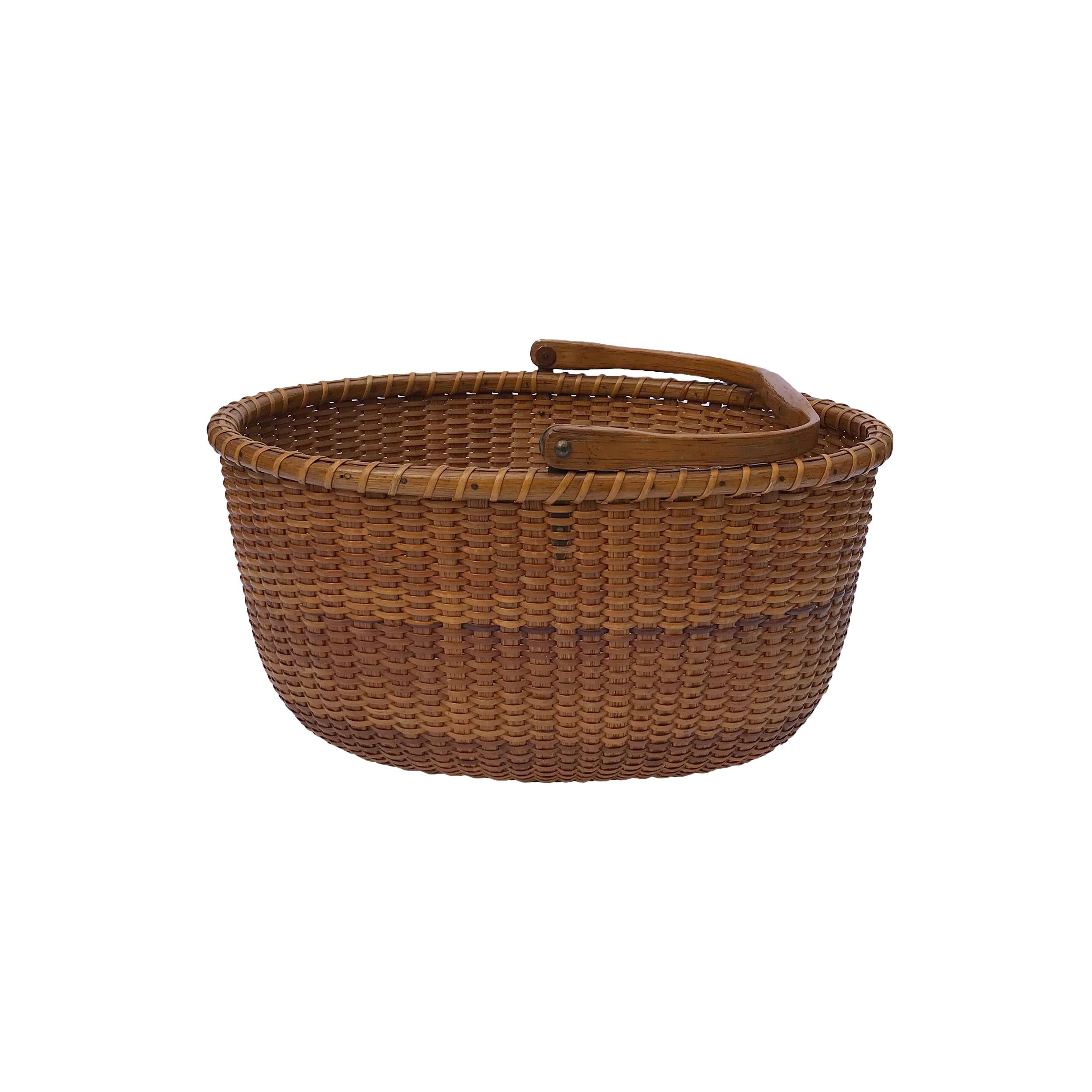 The basket has a warm honey patina, made with oak staves and swing handle, the handle has a brass pinned name plate attached to the top. The bottom plate is made out of Pine. Remnants of original paper label remains on the exterior bottom
Made by