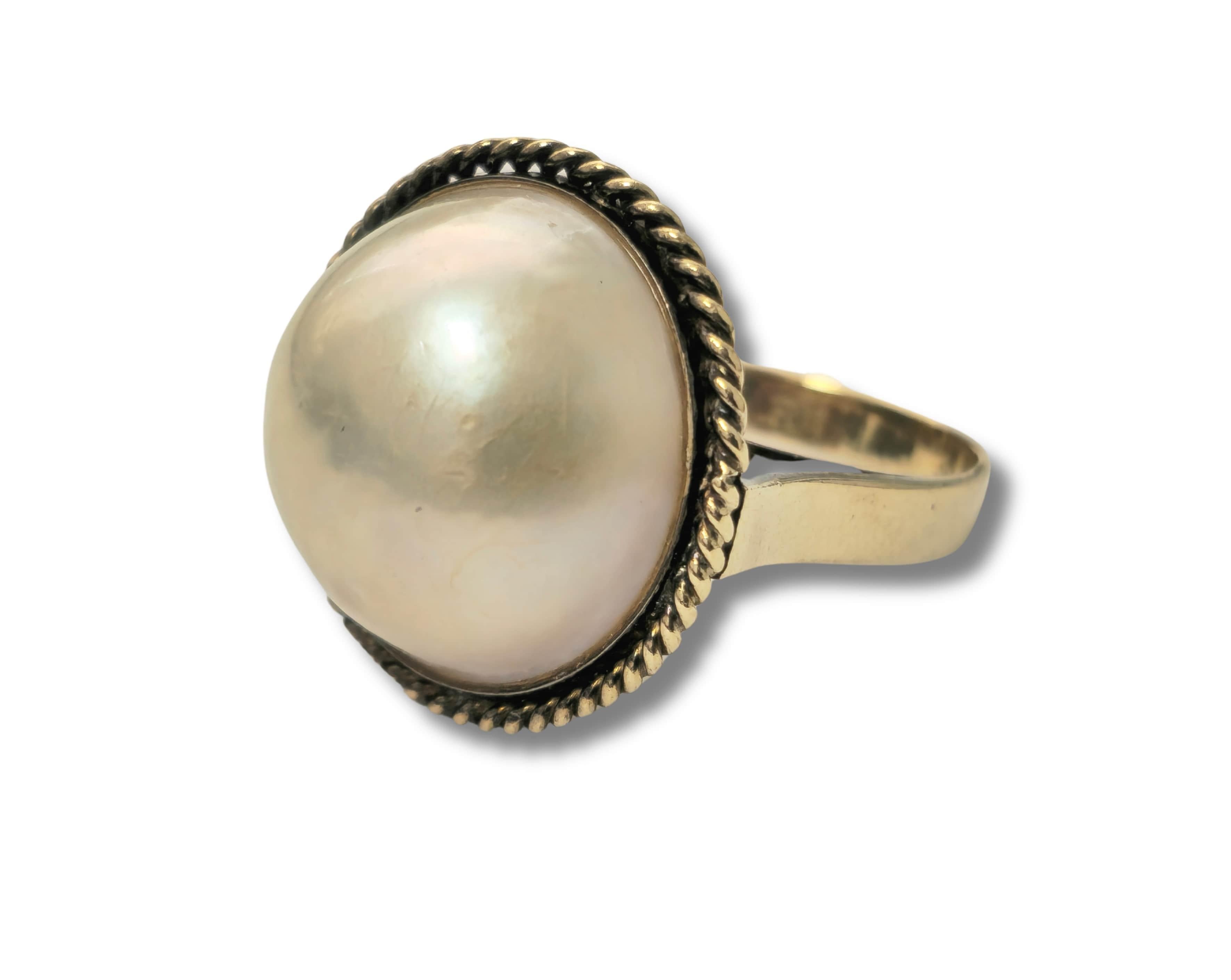 La sophistication intemporelle est de mise avec notre bague de perles anciennes pour femme, réalisée en luxueux or jaune 18 carats. Ornée d'une superbe perle de 13 carats, cette pièce exquise respire l'élégance et la grâce. Avec un poids total de