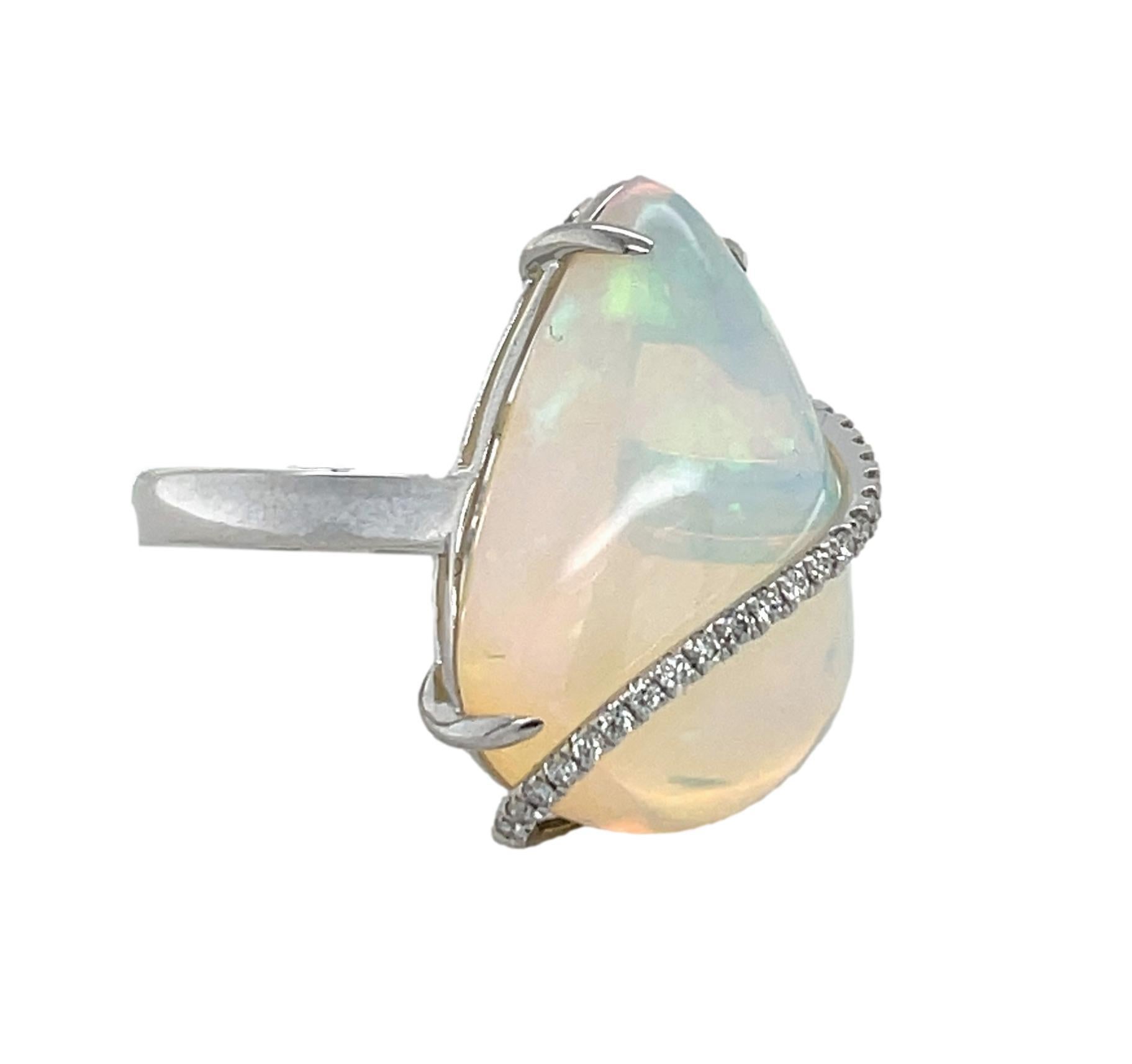 This stunning Statement ring has a 12.91 ct pear shape Ethiopian Opal with a swirl of 21 brilliant cut round diamonds elegantly crossing the stone. The Opal is 4 prong set in 14K white gold. This beautiful ring will be the talk of your special