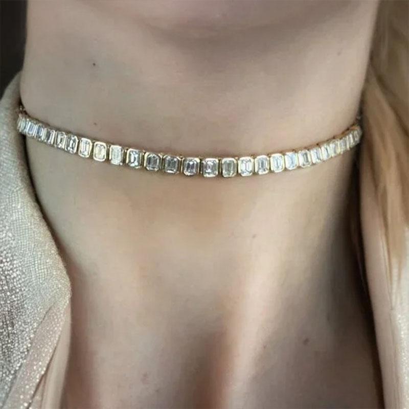 Elevate your neckline with understated elegance. This refined 14K gold choker features a captivating 13 pointer emerald-cut diamond, bezel set at the center for a clean, modern finish. The slim gold chain sits gracefully at the collarbone or neck,