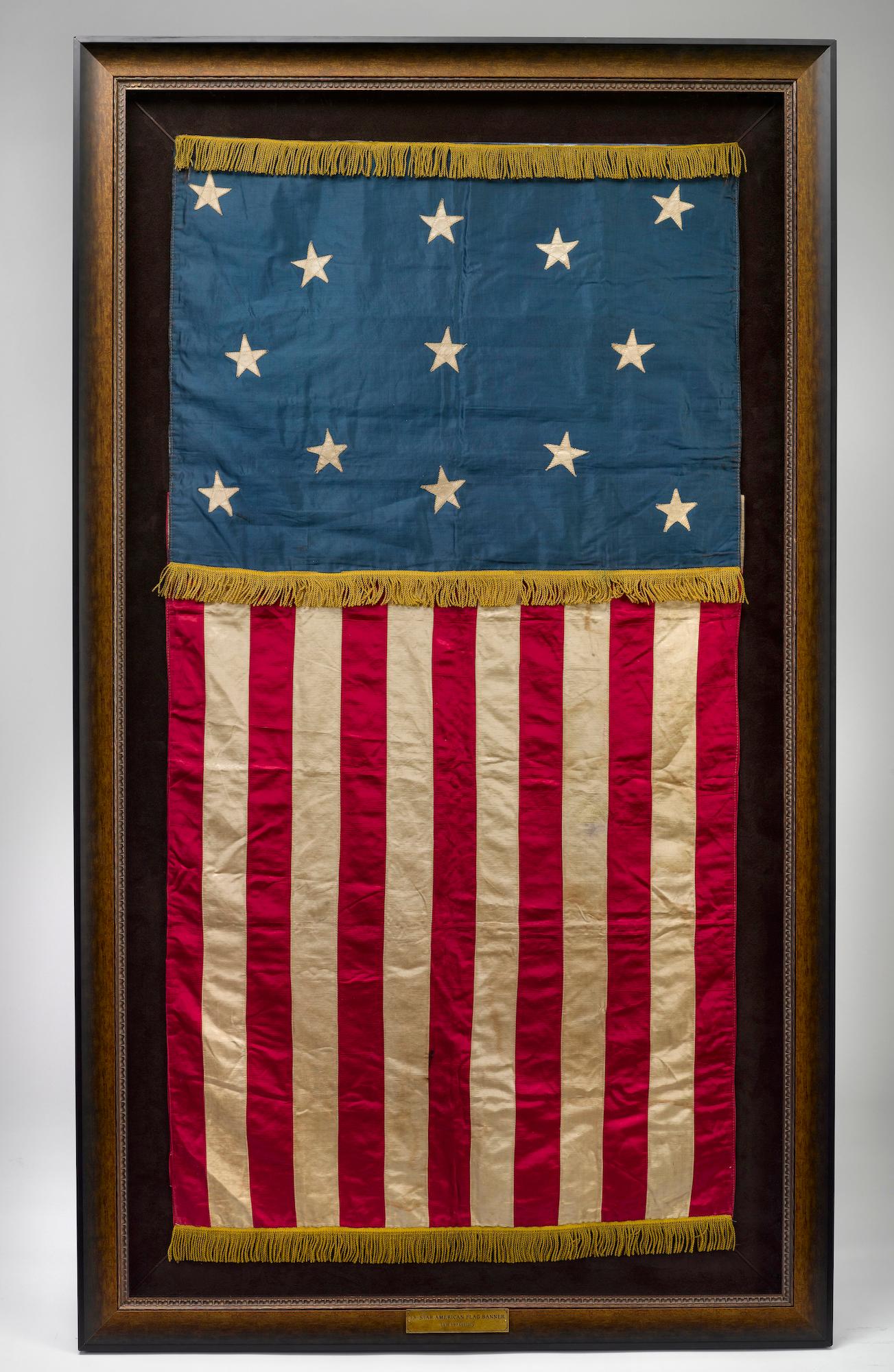 Presented is a large 13-star American flag banner, in a striking vertical format. The all-silk constructed banner features a rich blue canton with 13 white stars. The silk stars are machine-sewn, single appliquéd, and arranged in an unusual