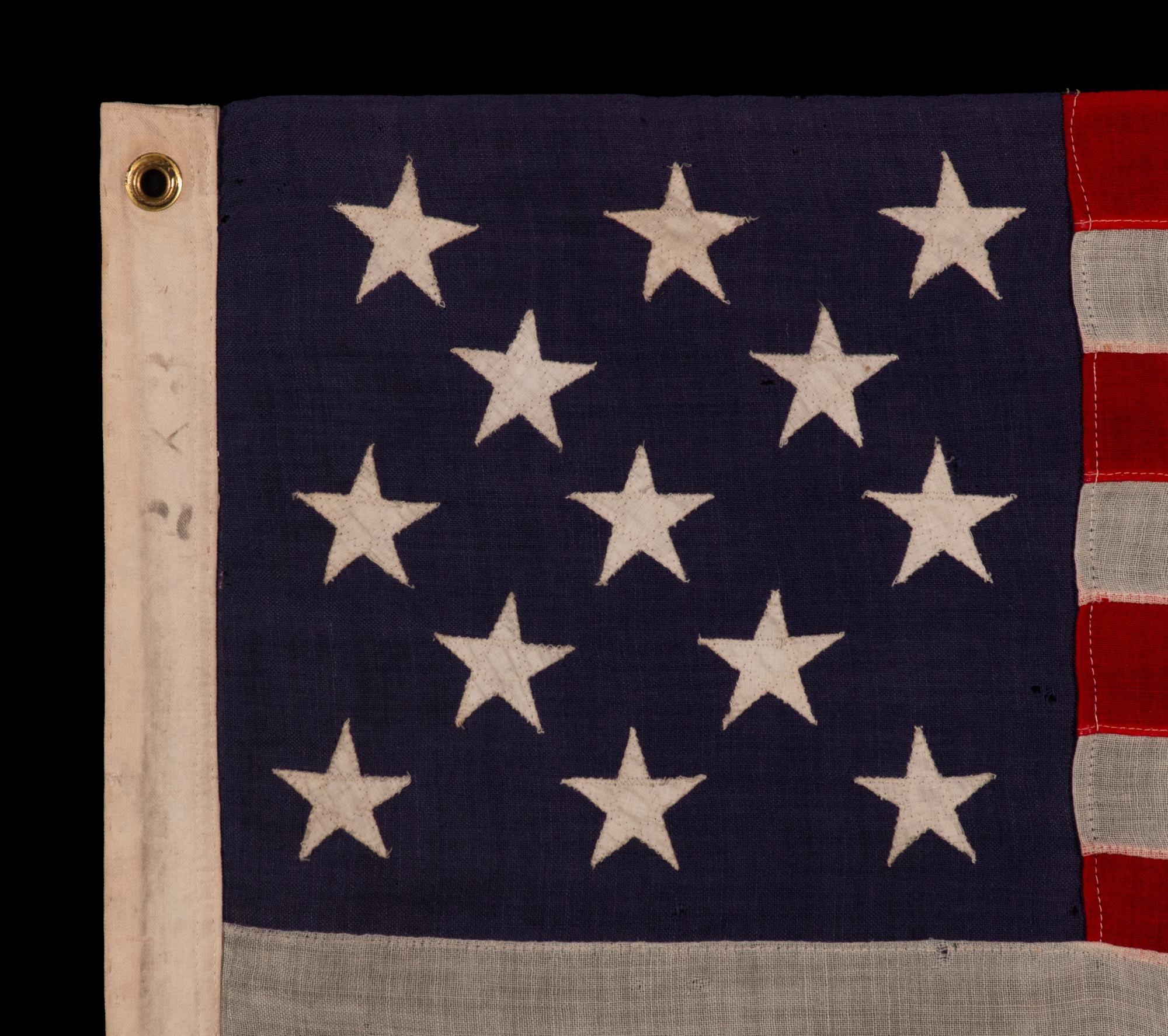 13 STAR ANTIQUE AMERICAN FLAG WITH A 3-2-3-2-3 CONFIGURATION OF STARS ON AN INDIGO CANTON, SQUARISH PROPORTIONS, AND A BEAUTIFUL GLOBAL PRESENTATION, MADE circa 1895-1926

Ce drapeau américain antique à 13 étoiles est d'un type fabriqué au cours de