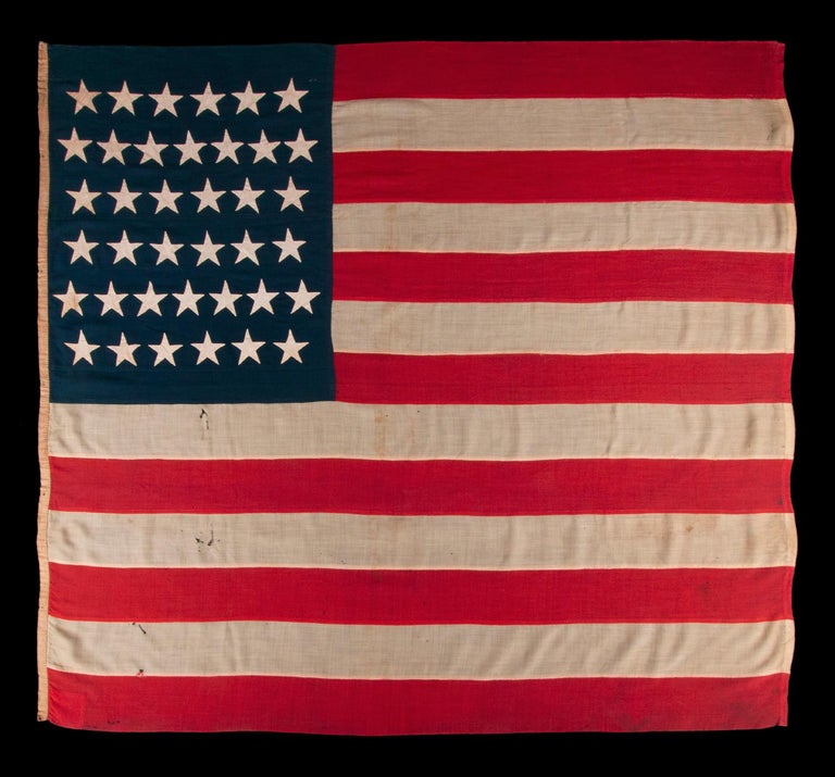 38 STAR ANTIQUE AMERICAN FLAG OF THE INDIAN WARS PERIOD, A U.S. ARMY REGULATION BATTLE FLAG, ENTIRELY HAND-SEWN, 1876-1889, SIGNED 