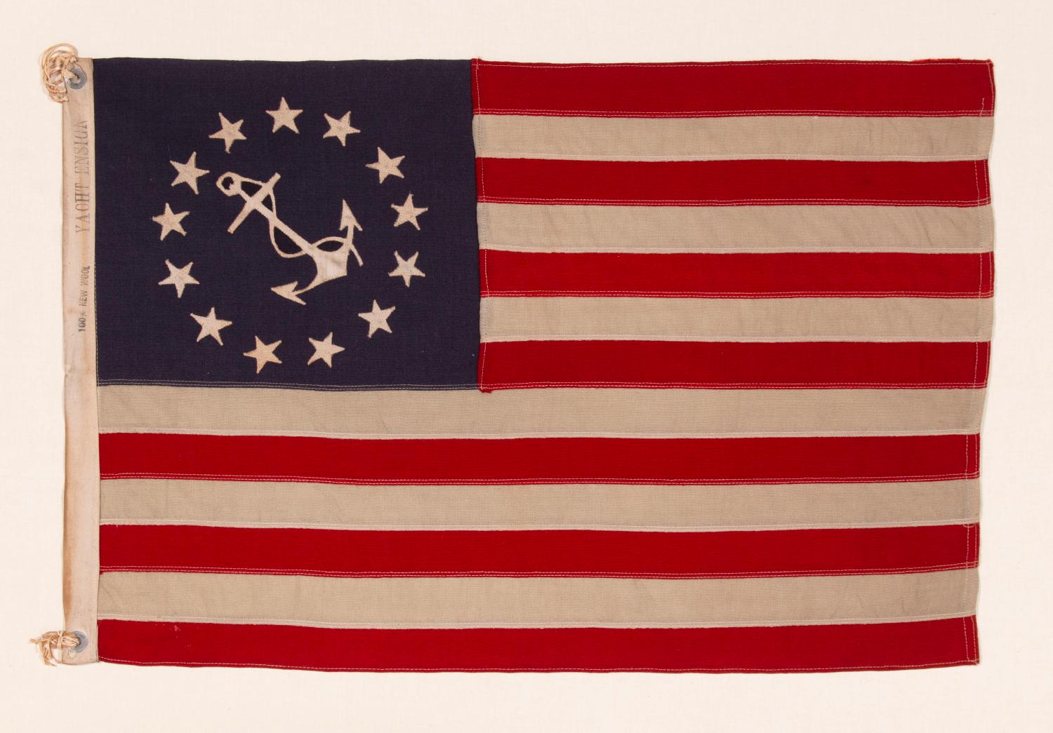 ANTIQUE AMERICAN PRIVATE YACHT FLAG (ENSIGN) WITH 13 STARS SURROUNDING A CANTED ANCHOR, CIRCA 1910 – 1920’s 

The medallion configuration, 13-star, 13-stripe flag with a canted center anchor was entered into official use in 1848, following an act of