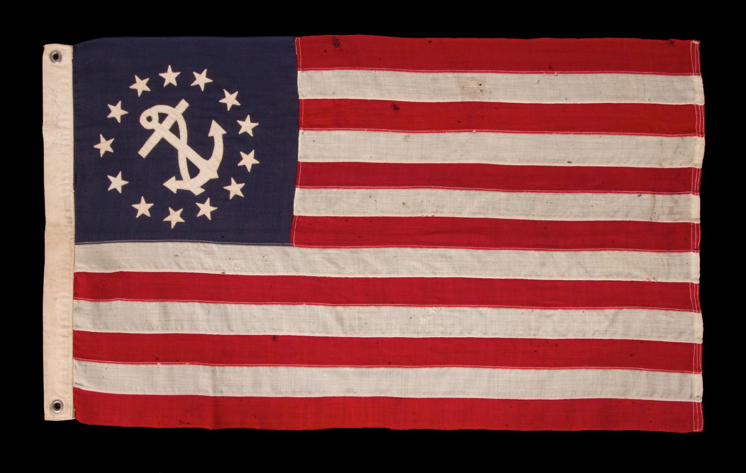Antique American Private Yacht Flag (Ensign) With 13 Stars Surrounding A Canted Anchor, An Attractive, Elongated Example With An Off-set Device, circa 1905–1920.

The medallion configuration, 13-star, 13-stripe flag with a canted center anchor was