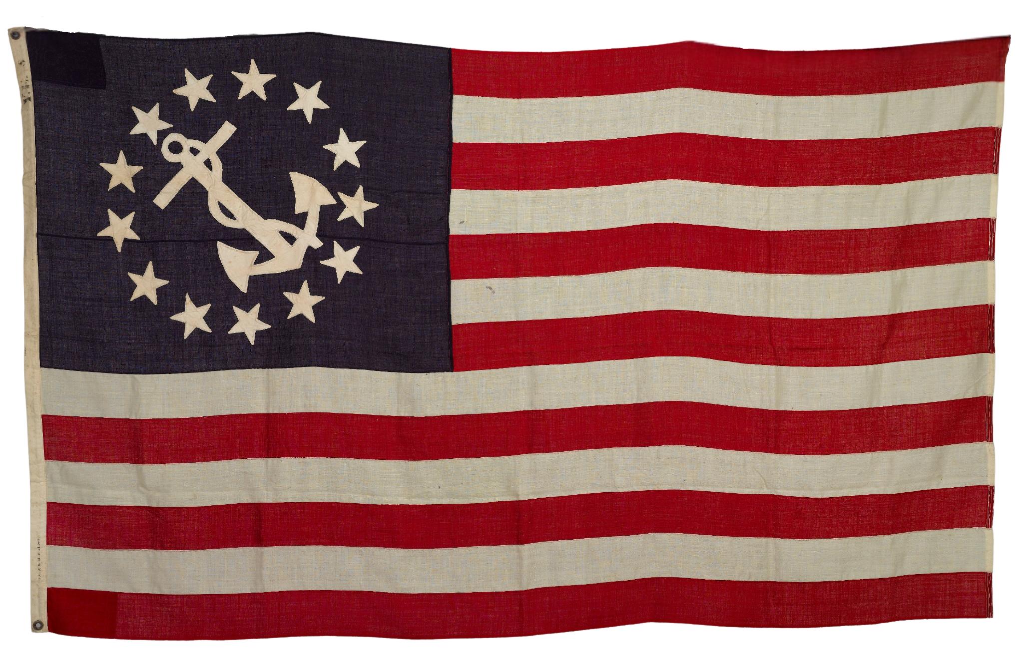 Presented is a 13-star Yacht Ensign from the early 20th century, dated 1900-1925. The machine-sewn canton has 13 single-appliqued white cotton stars arranged in a medallion, enclosing a white fouled anchor on blue bunting. The design is completed