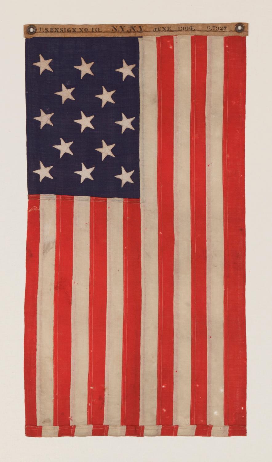 13 STARS IN A 3-2-3-2-3 PATTERN ON A UNITED STATES NAVY SMALL BOAT ENSIGN OF EXCEPTIONALLY SMALL SCALE, MADE AT THE BROOKLYN NAVY YARD, NEW YORK, SIGNED & DATED 1906 


13 star American national flag of the type used by the U.S. Navy on small boats