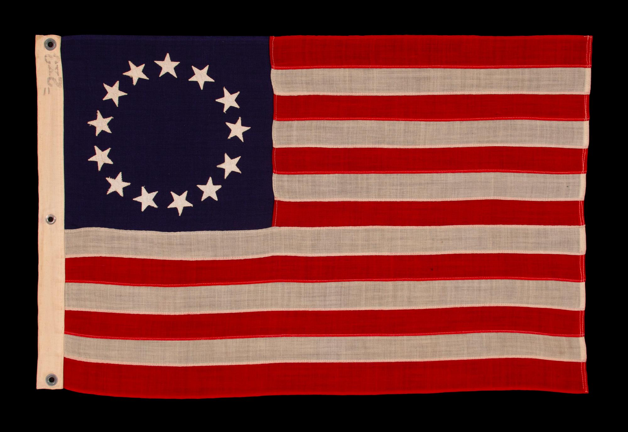13 STARS IN THE BETSY ROSS PATTERN ON A SMALL-SCALE ANTIQUE AMERICAN FLAG MADE SOMETIME BETWEEN APPROXIMATELY 1910 AND THE 1926 SESQUICENTENNIAL OF AMERICAN INDEPENDENCE

13 star flag of the type made from roughly the last decade of the 19th century