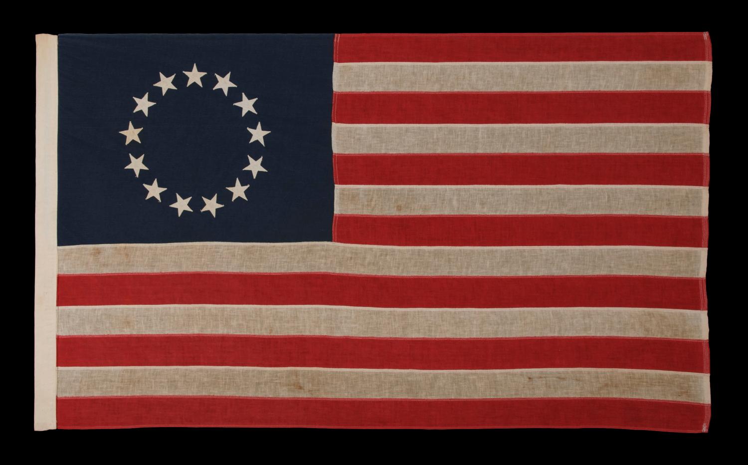 13 STARS IN THE BETSY ROSS PATTERN, A SCARCE SEWN EXAMPLE IN A DESIRABLE SMALL SCALE, 1900-1930: 

13 star American national flag, made in the period between approximately 1900 and 1930. The stars are arranged in the circular wreath pattern most