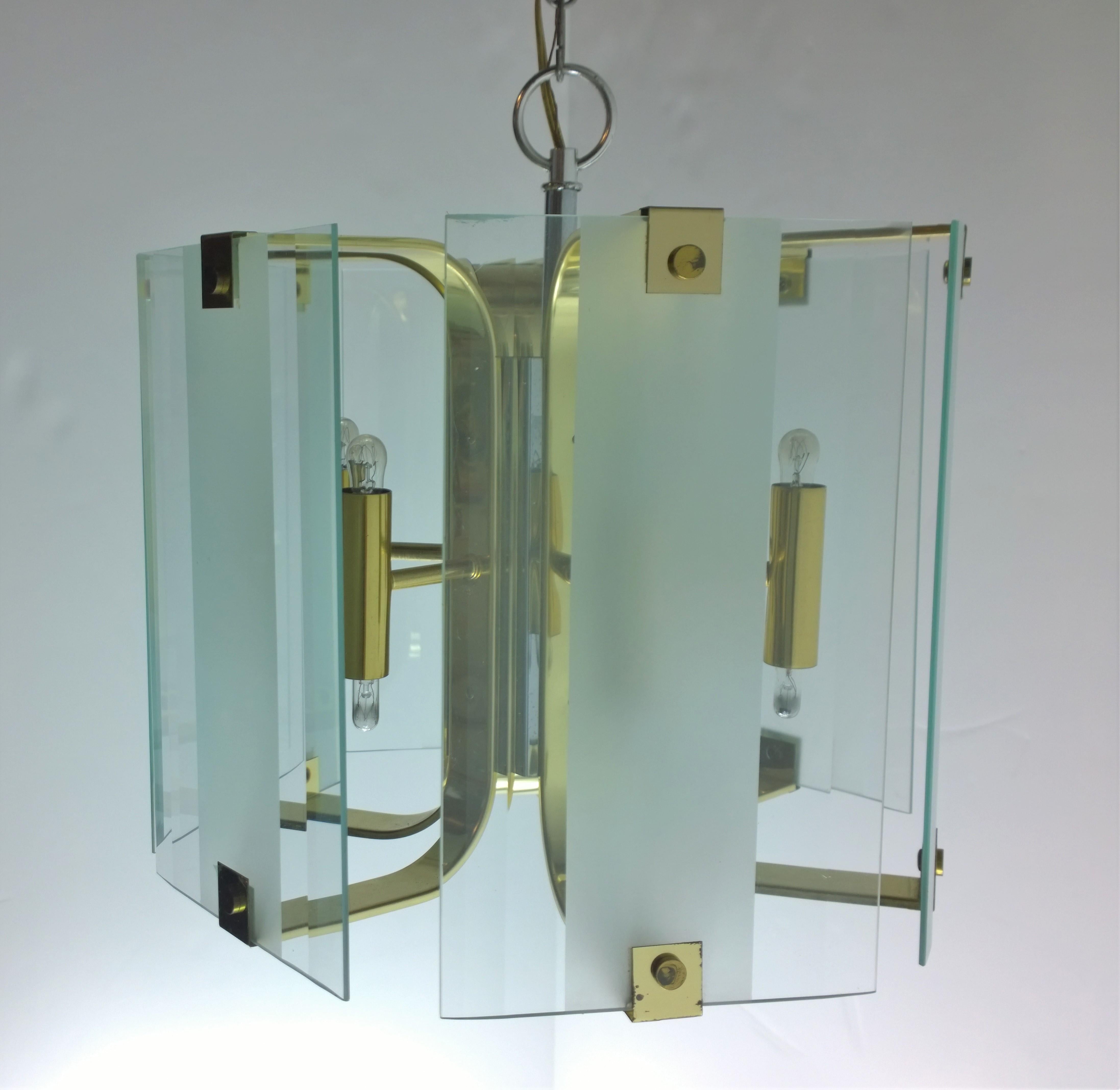 Offered is a Mid-Century Modern clear and frosted glass and brass chandelier by Fredrick Raymond. This chandelier is a true example of Classic modern 1970s and 1980s design. This sophisticated and chic fixture has six glass panels alternating
