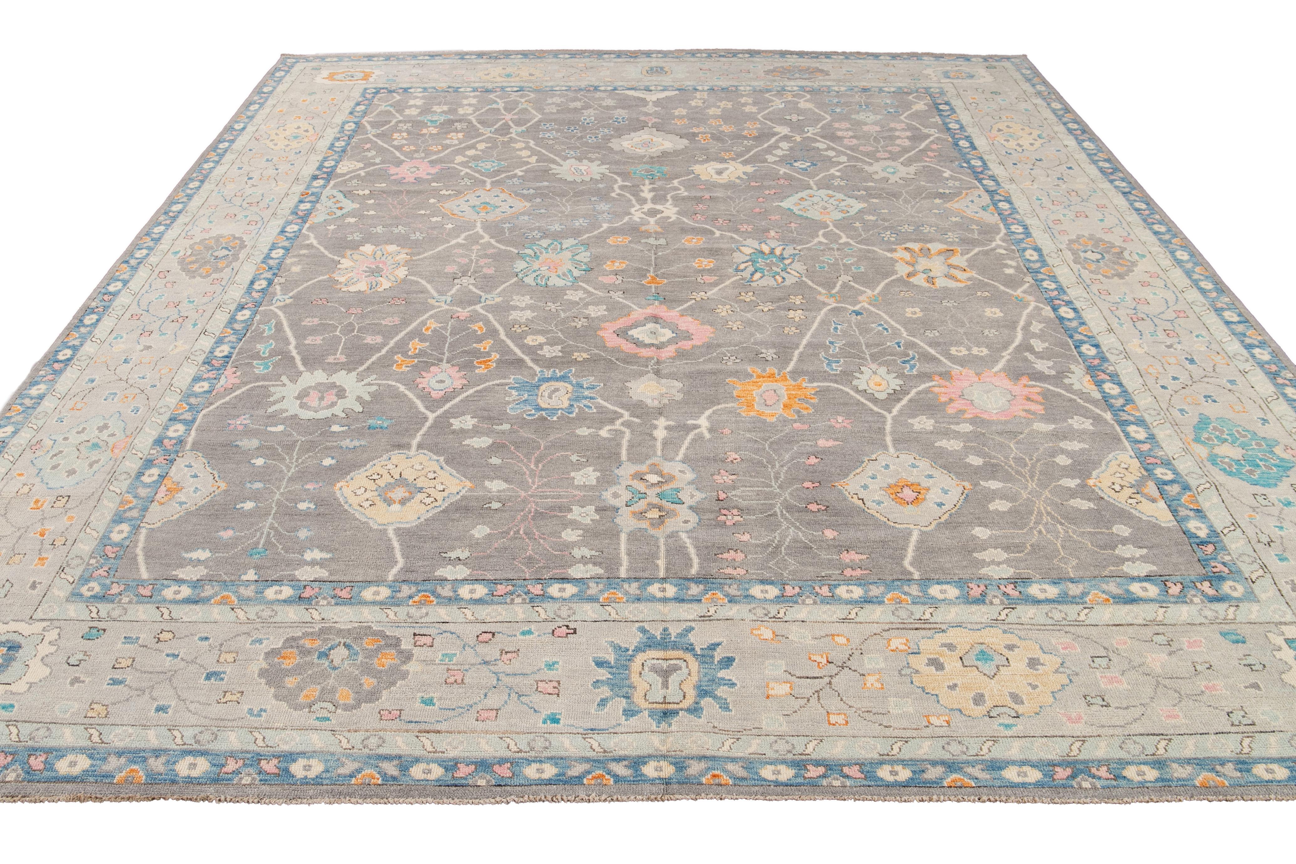 Questo moderno tappeto in lana in stile Oushak, annodato a mano, presenta un sottile sfondo grigio ornato da motivi floreali. Il suo design combina l'estetica contemporanea con l'artigianato tradizionale di Oushak. I colori e i motivi vivaci possono