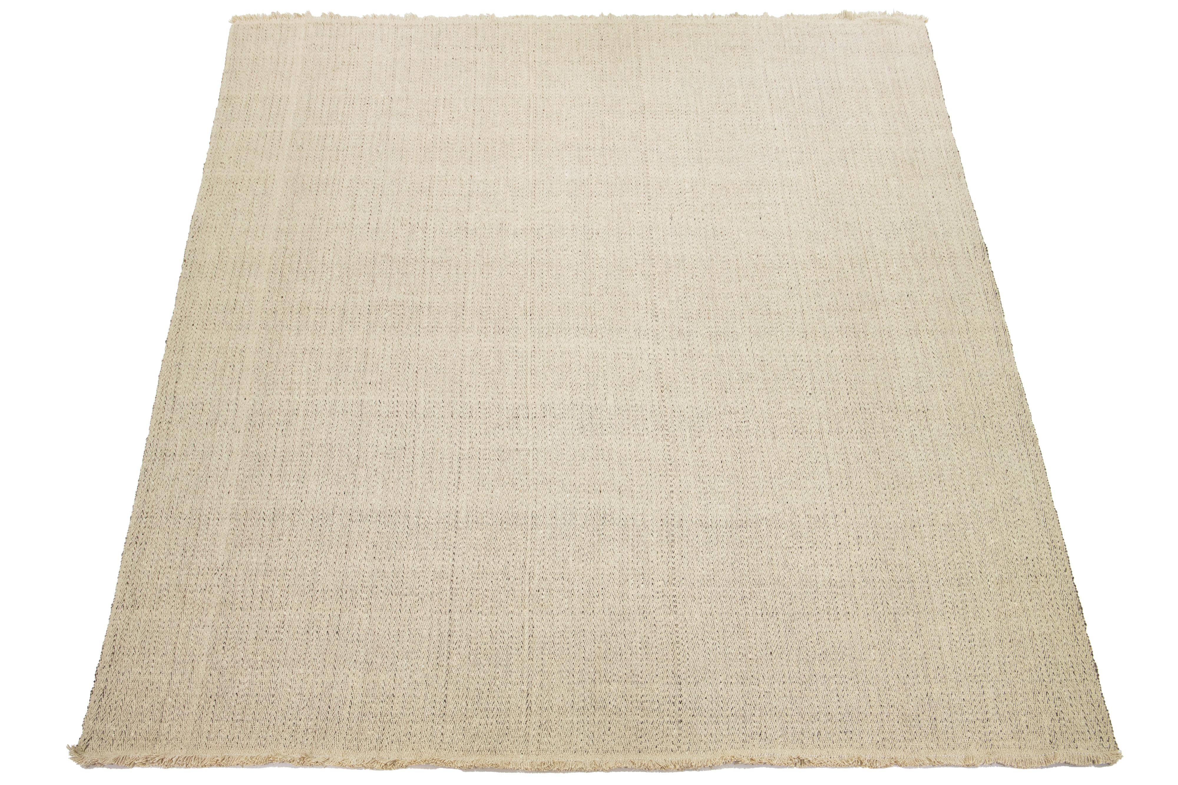 Dieser Teppich zeichnet sich durch ein modernes Flachgewebe aus organischer Wolle mit einem beige-grauen Grundmuster aus. 

Dieser Teppich misst 12'6