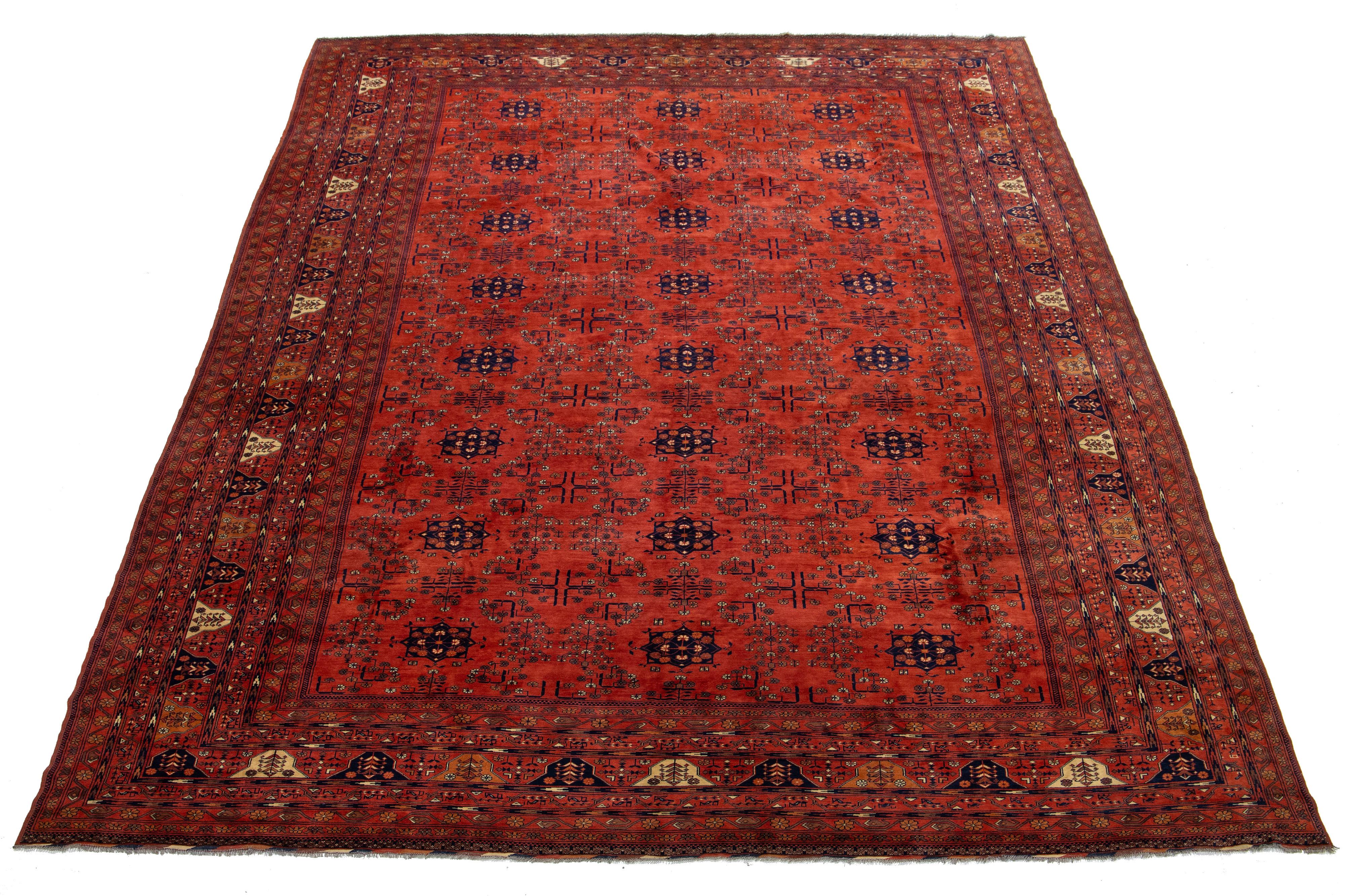 Ein übergroßer afghanischer Wollteppich im Vintage-Stil mit blauem, beigem und orangefarbenem Muster auf rotem Hintergrund.

Dieser Teppich misst 13'2' x 18'11