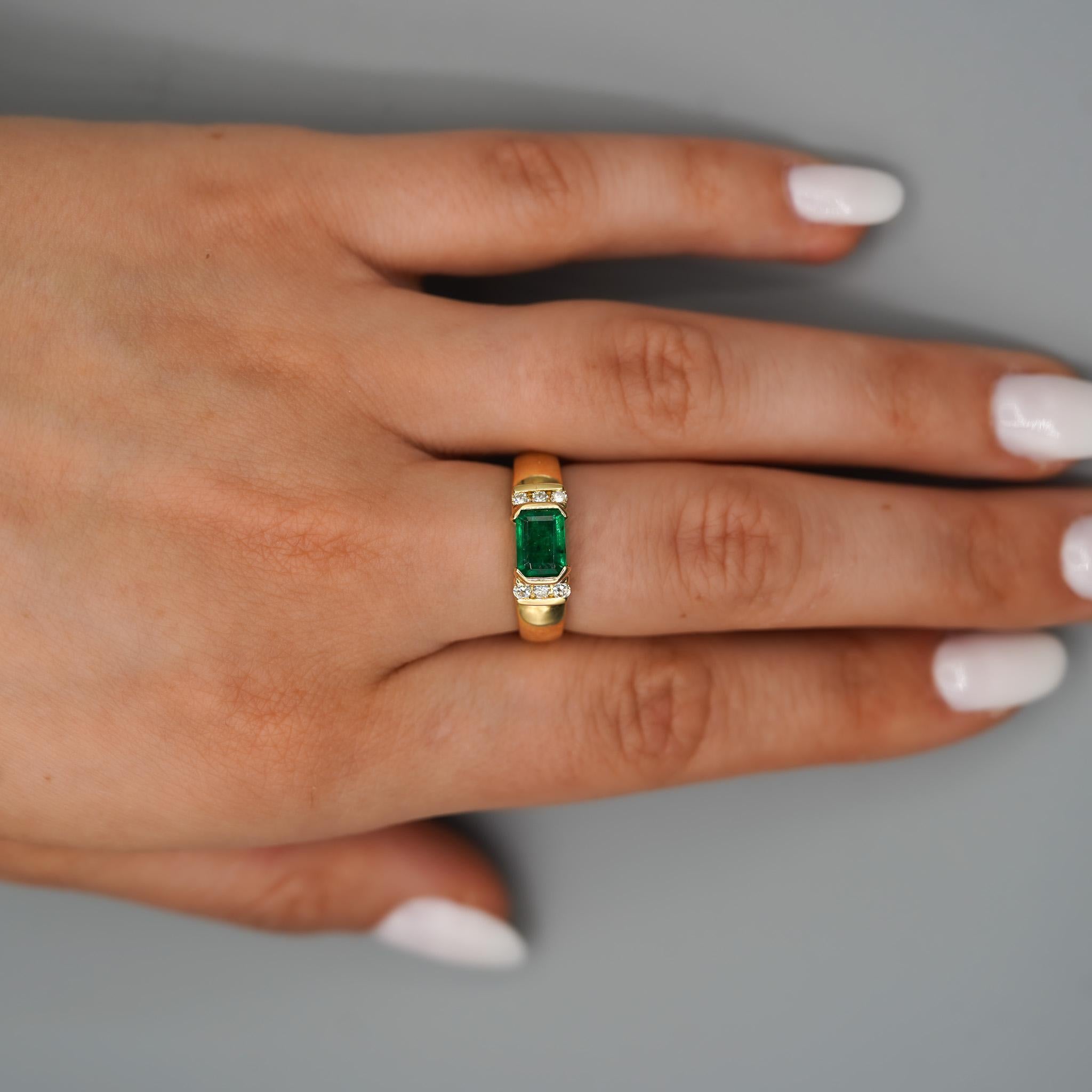 Half bezel east west set A striking emerald cut 1.30 carat emerald is flanked by channel set round cut diamond accents in a 14K yellow gold ring. With a wide, smooth band and bold vintage styling, this ring is made to stand out. Unisex.

Ring size