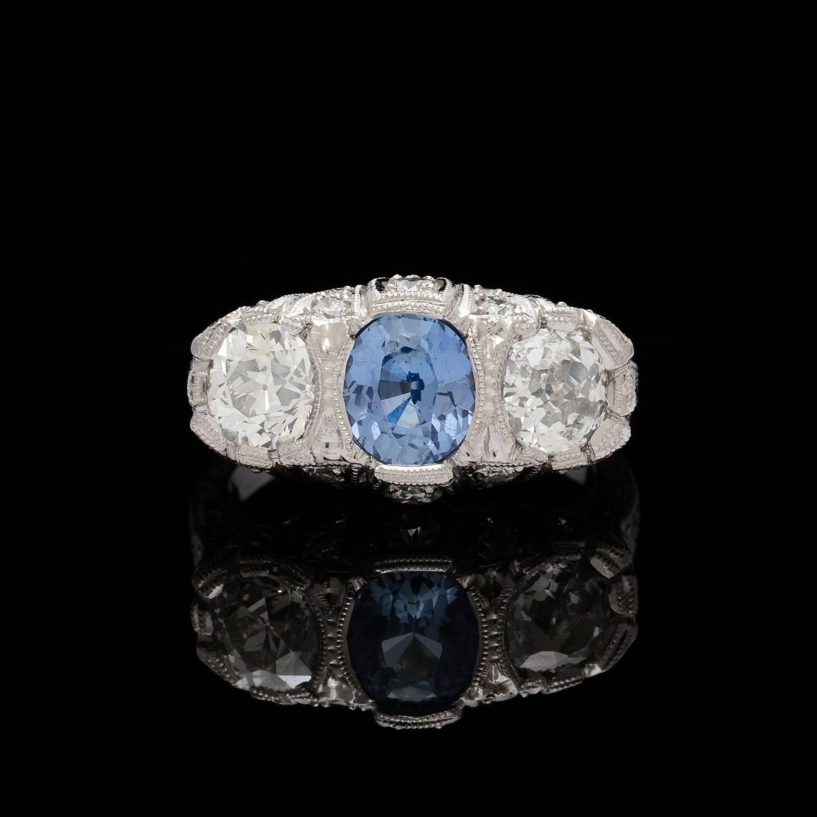 Platinum 3-stone filigree ring features a center GIA 1.30 carat oval cut unheated sapphire. The color is described as violetish blue, report # 1106710481 accompanies the sapphire. Set on each side of the sapphire are old european cut diamonds