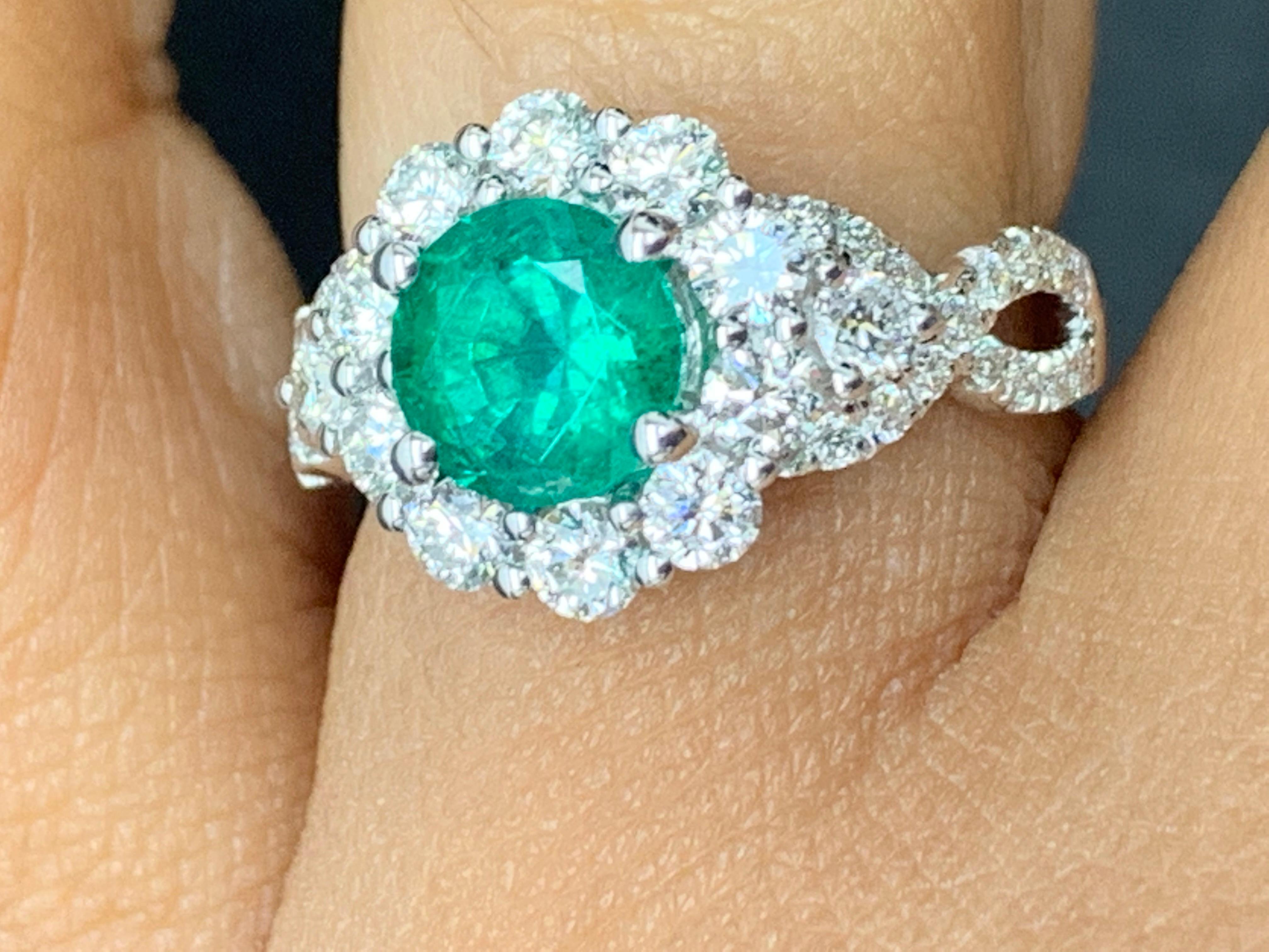 Features a gorgeous flower design  1.30 carat round cut lush green emerald ring surrounded by a row of brilliant-cut 12 diamonds weighing 0.88 carats in total. Embellished with two cris cross rows of round cut diamonds. Made in 18k white gold.