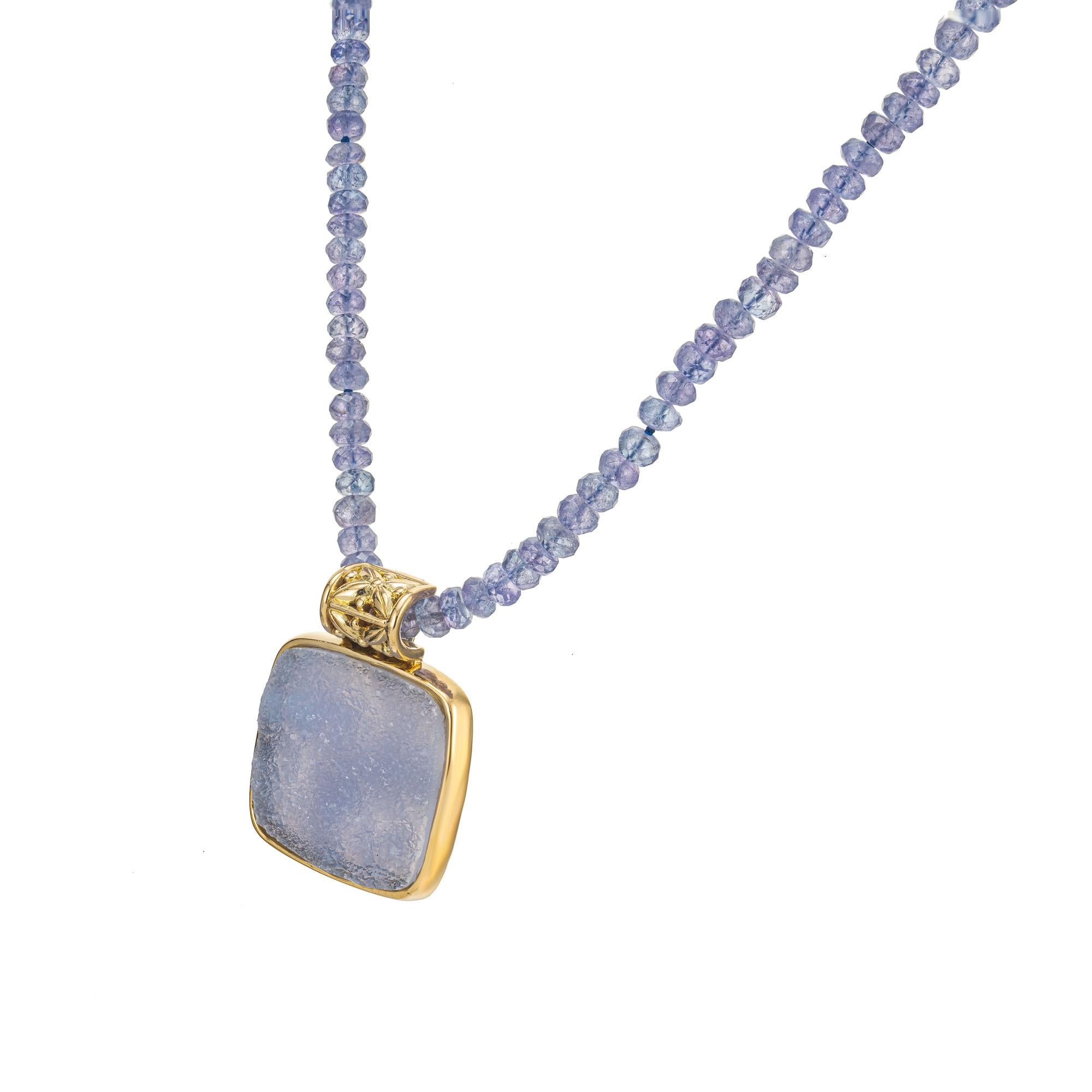 Blue druzy quartz crystal in an 18k yellow gold frame with enhancer bail on a strand of faceted tanzanite beads with a toggle catch. 17 inches long. 

1 square slab periwinkle blue quartz, approx. 13.00cts
145 tanzanite purplish blue faceted beads,