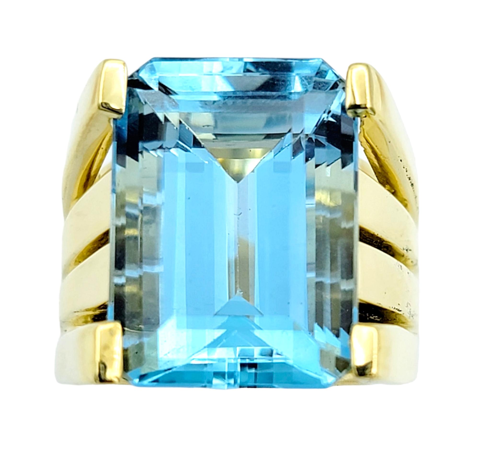 Ring size: 5.5

This extraordinary cocktail ring showcases a mesmerizing 13.05 carat emerald-cut aquamarine, cradled within an exquisite setting of opulent 18 karat yellow gold. The aquamarine's clarity and depth of color are nothing short of