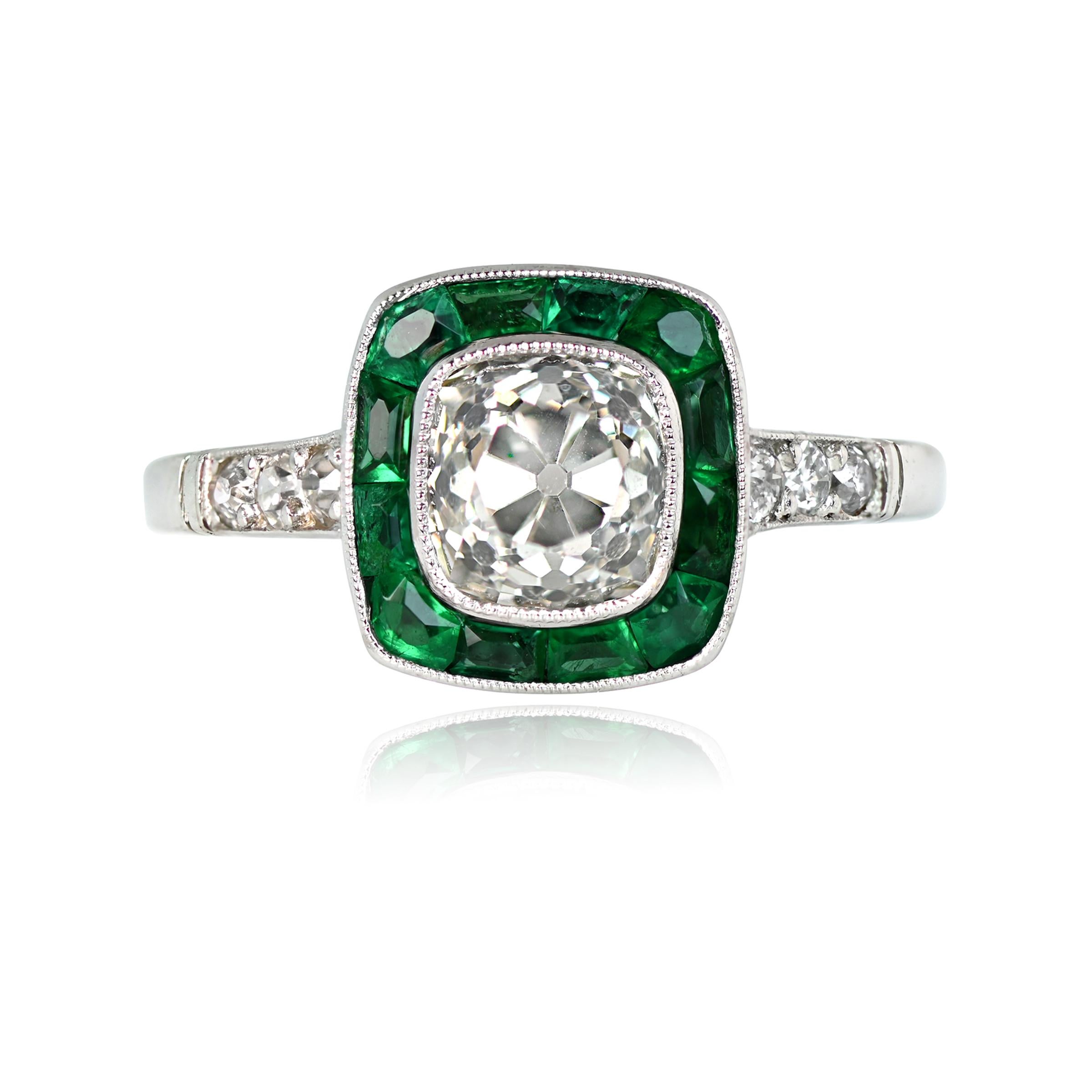 An emerald halo diamond engagement ring showcases a central 1.30-carat antique cushion cut diamond, exhibiting K color and VS2 clarity. The center diamond is embraced by a square-shaped bezel adorned with natural faceted calibre emeralds, adding a
