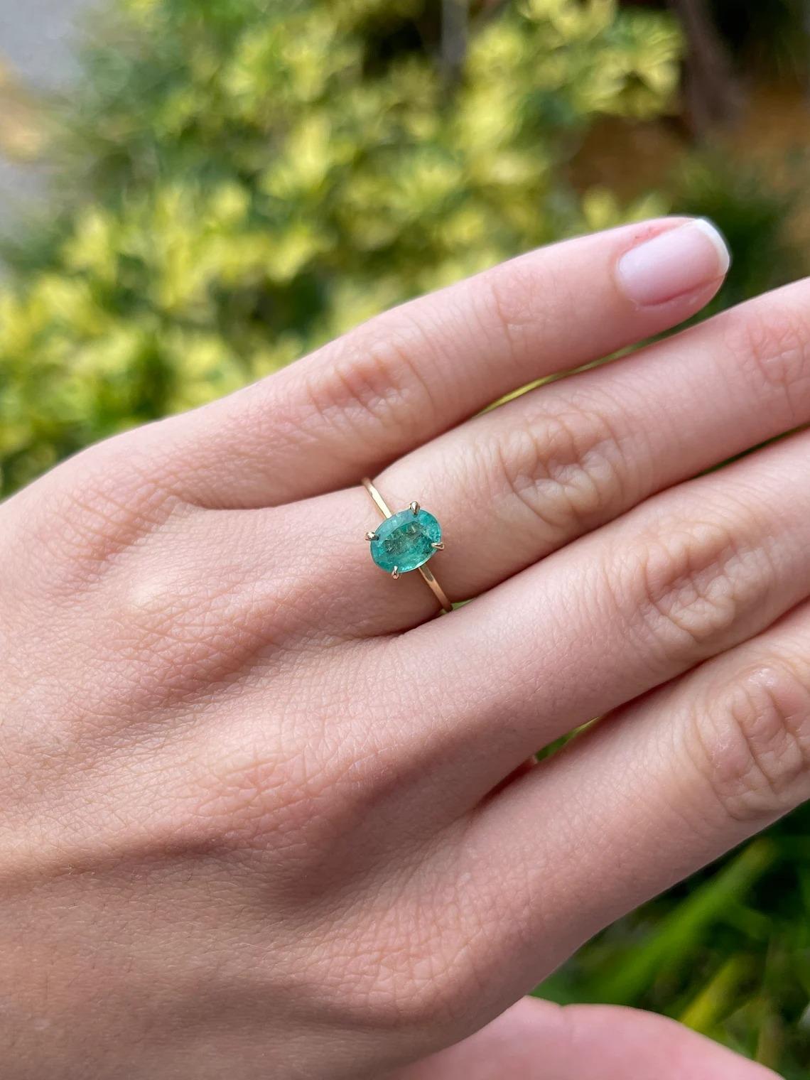 Displayed is a custom emerald solitaire oval-cut ring in 14K yellow gold. This gorgeous solitaire ring carries a 1.30-carat emerald in a prong setting. The emerald has very good clarity with minor flaws that are normal in all genuine emeralds. The
