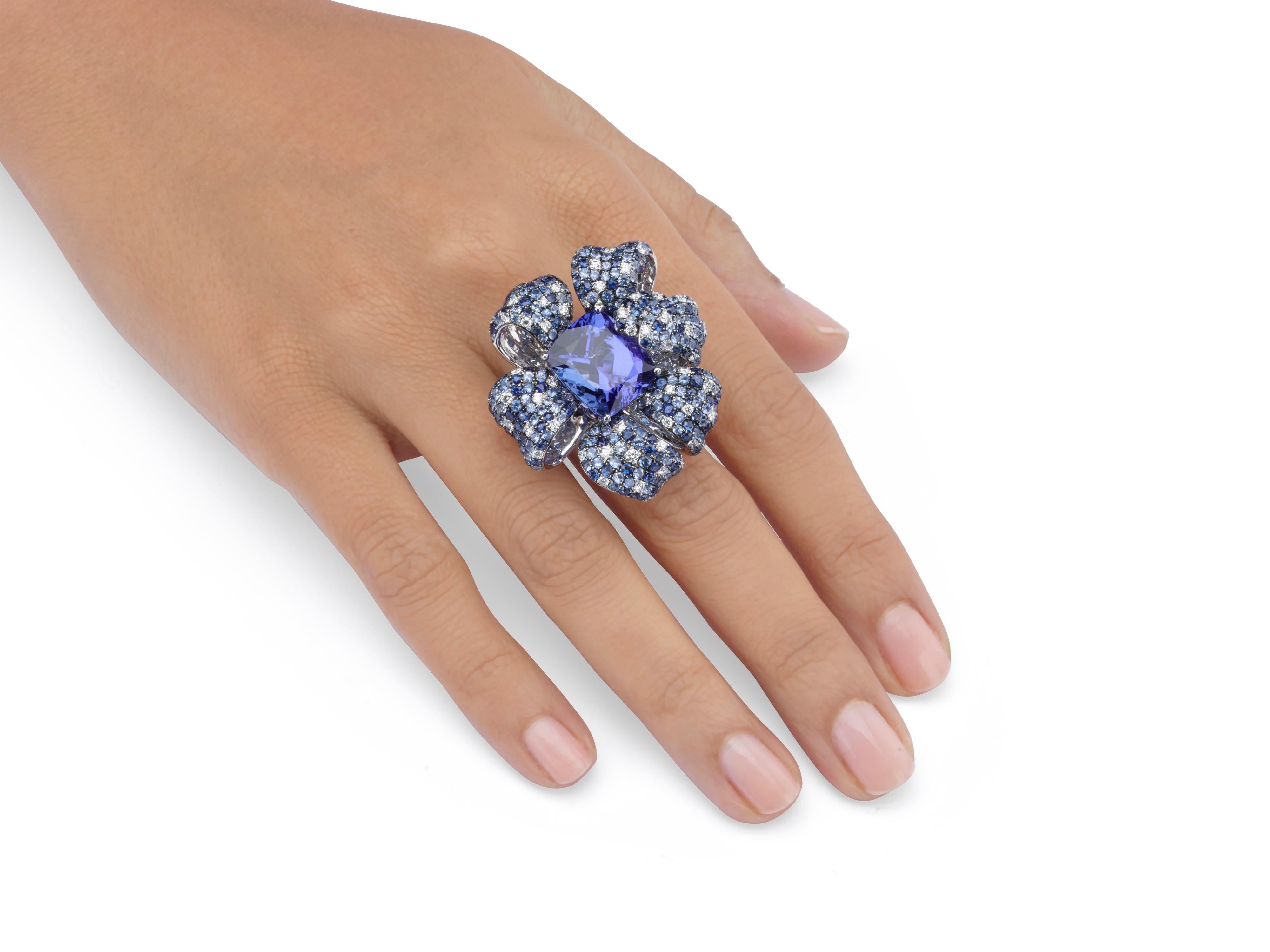 Butani's one-of-a-kind Trumpet Flower Ring features a floral silhouette with a stunning 13.12 carat blue cushion-cut tanzanite center, 7.8 carats of blue sapphires 1.29 carats of white round diamond-encrusted petals.  Set in 18K white