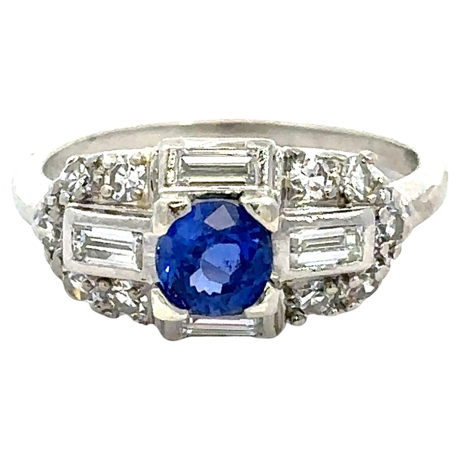 This Stunning Vintage Platinum Art Deco Ring dates from The 1950's.
It Features One Round Stunning Blue Natural .64CT Sapphire.
The Setting has .68ct Round and Baguette Stunning Diamonds
F-H Color  VS-SI Clarity. 
The Top of The Ring Measures 16mm