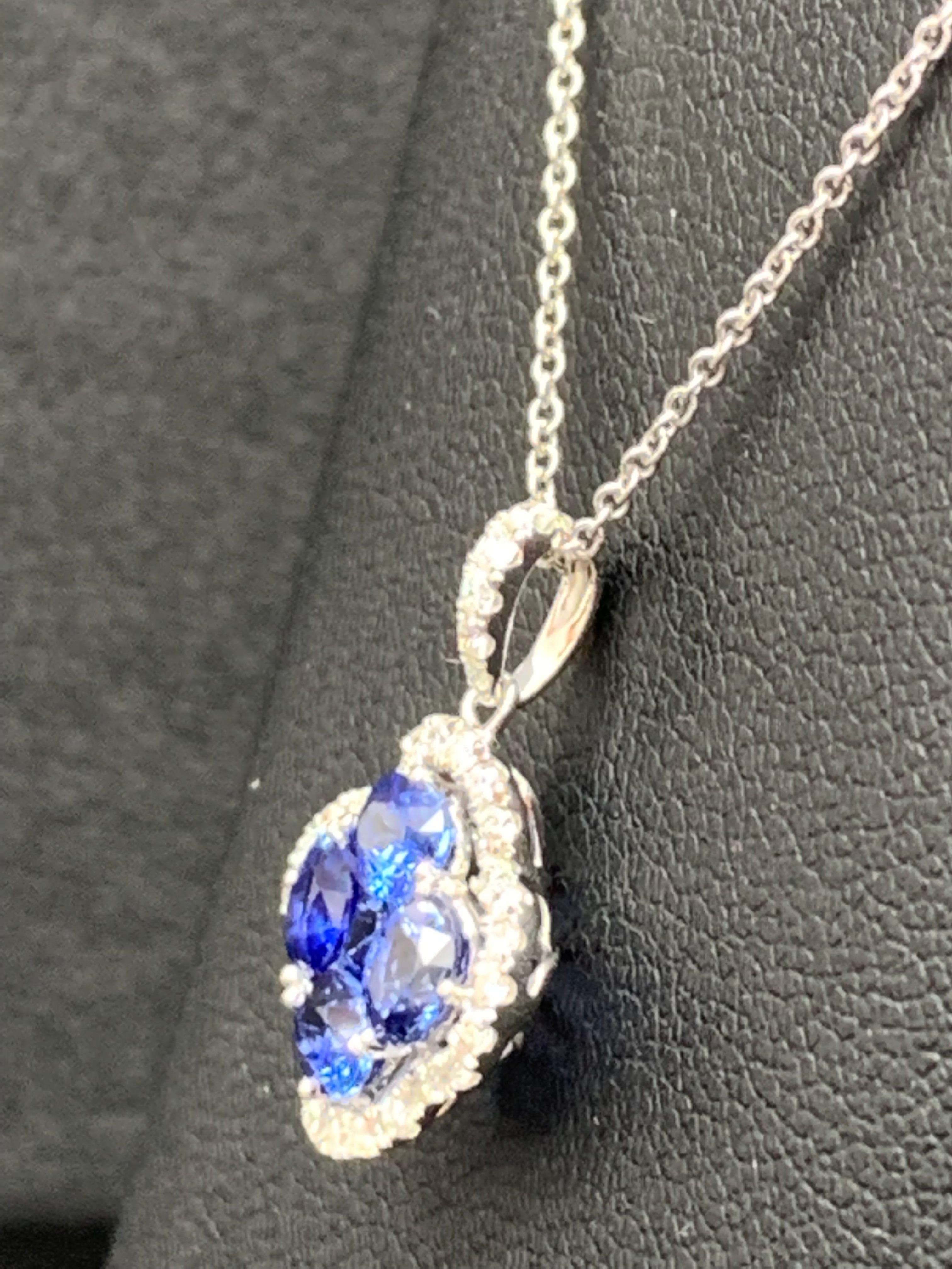 Showcasing flower design pendant with 4 oval shape Blue Sapphires weighing 1.33 carats total and 1 round shape Blue Sapphire weighing 0.13 carat, accented by a row of 33 round brilliant diamonds. Diamonds weigh 0.25 carats total. Set in a polished