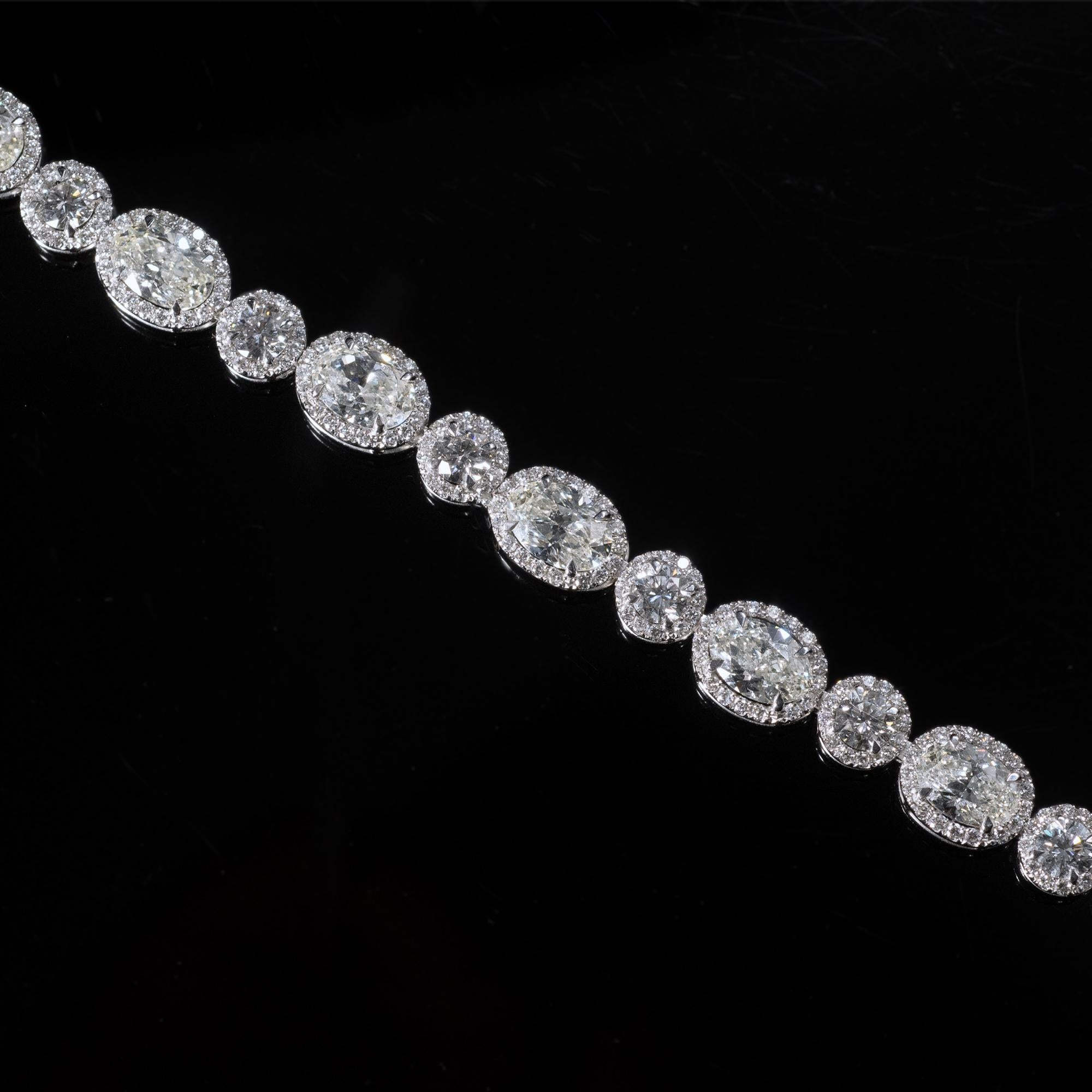 Exceptional 18 karat gold and diamond tennis bracelet: Twelve oval cut diamond about 0.75 carat each alternating with twelve round brilliant cut diamond each about 0.22 carat. 
Each of these central stones are surrounded in a halo like pattern by