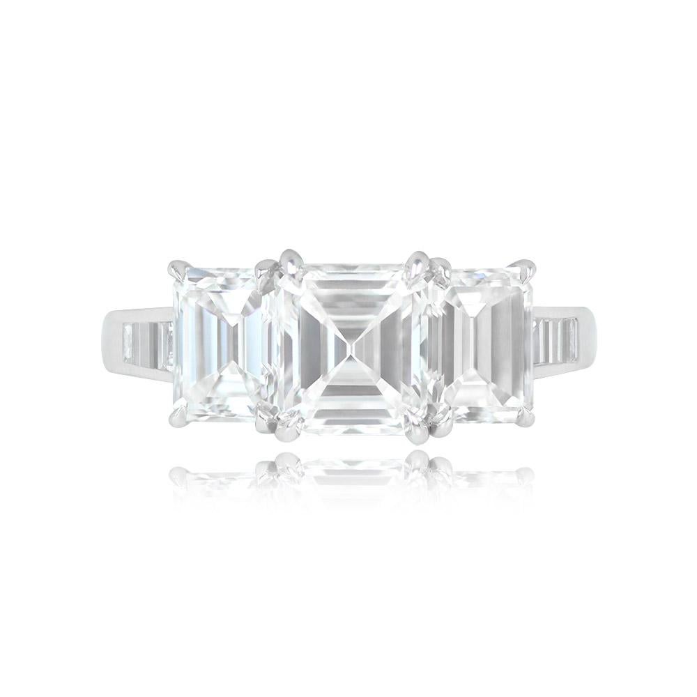 This exquisite three-stone engagement ring showcases a 1.33-carat Asscher-cut diamond at its center, boasting a splendid G color and VS2 clarity. Flanking the central diamond are two emerald-cut diamonds weighing 0.79 carats and 0.80 carats, both