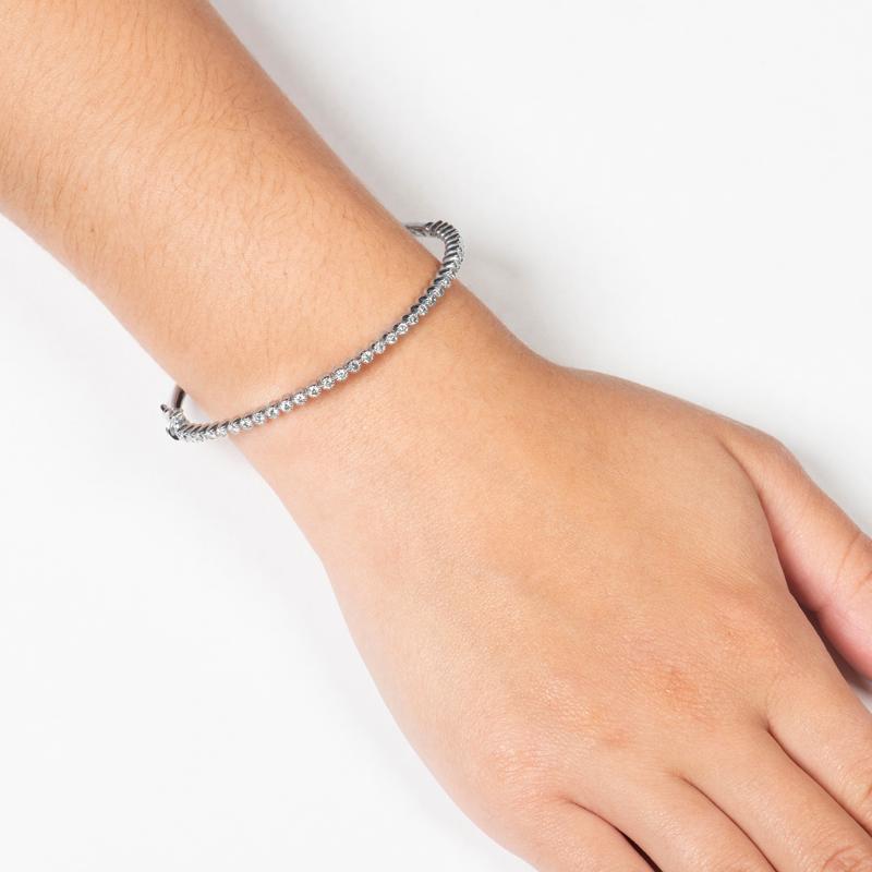 This dainty hinged bangle bracelet includes 35 bezel-set round diamonds with a 1.33ct total weight, set in 14kt white gold, finished with milgrain edges. This bracelet is perfect for layering and stacking with other bangle bracelets. The bracelet is