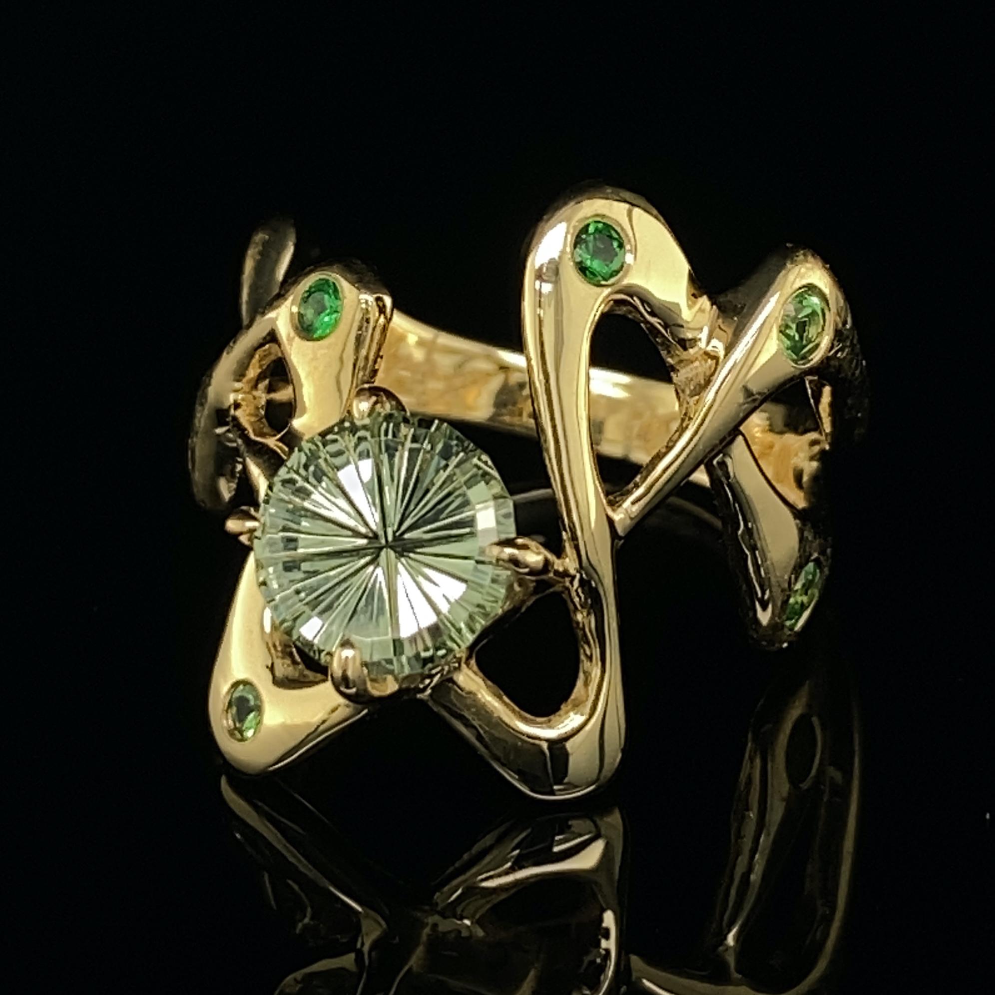 This outstanding ring boasts artistry from two master craftsmen:  the ring is by Eytan Brandes -- a freeform doodle of 18 karat gold dotted with six vivid green tsavorite garnets.  The main stone is a Montana sapphire cut by award-winning gemcutter