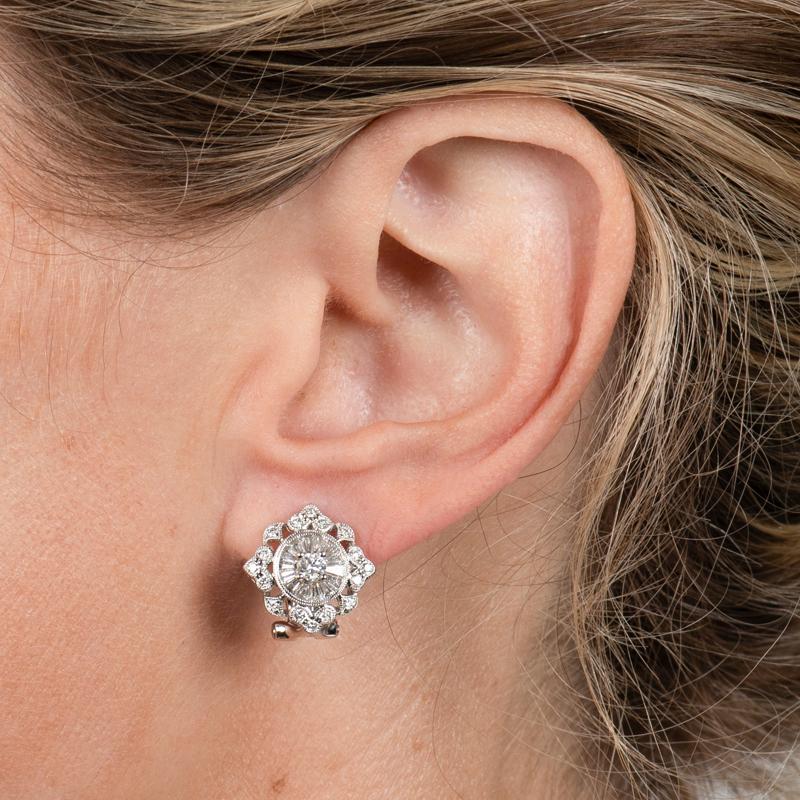 These vintage style earrings feature 1.34 carat total weight in round and tapered baguette diamonds set in 18 karat white gold. They are accented with milgrain detailing. Omega clip and post. 
Measurements: Approximately 14.50mm x 14.50mm