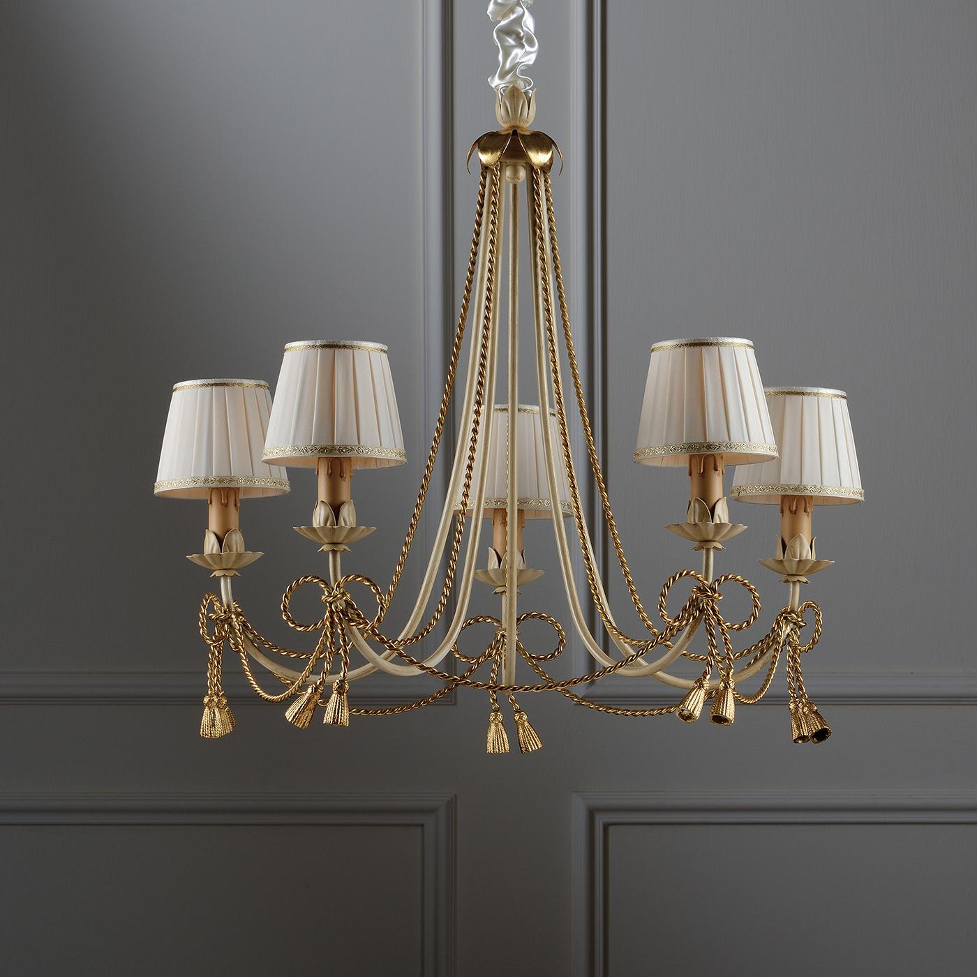 This is a majestic chandelier characterized by its ivory-colored metal structure that is further enhanced by details in gold leaf. It provides a fantastic and uniform illumination with 5 lights, all covered by deluxe lampshades in ivory-colored