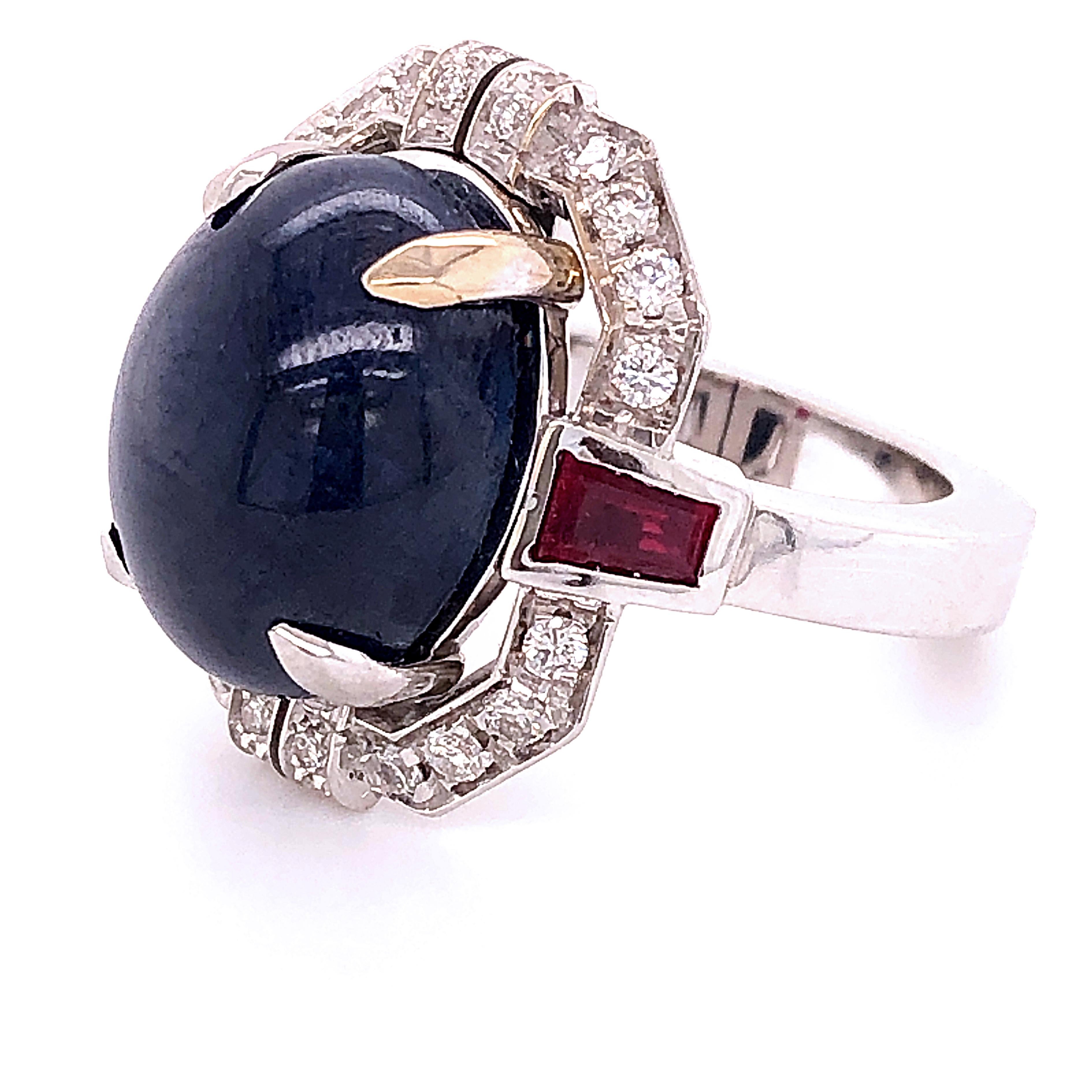 One-of-a-kind, Unique yet Timeless Cocktail Ring featuring a 13.48 Carat Natural Oval Sapphire Cabochon, two 0.66 Kt Carat Ruby Tapered Baguette in a chic 0.42 Kt White Diamond 18K White Gold Setting.
A detailed Gemological Certificate will be