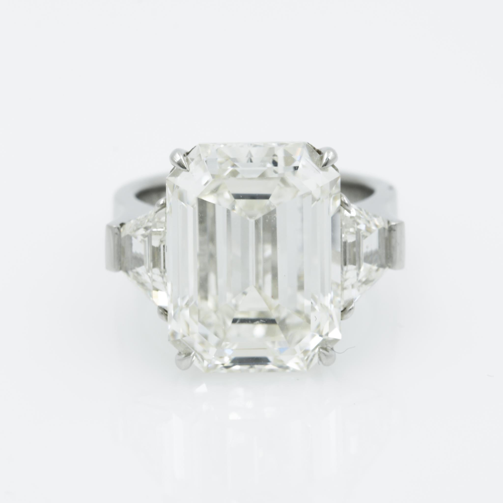 Go classic with this approximately 15 carat total weight, three stone emerald and trapezoid cut diamond ring. The approximately 13.49 carat emerald cut diamond has J color with VS1 clarity and is GIA certified. The center diamond is paired with two