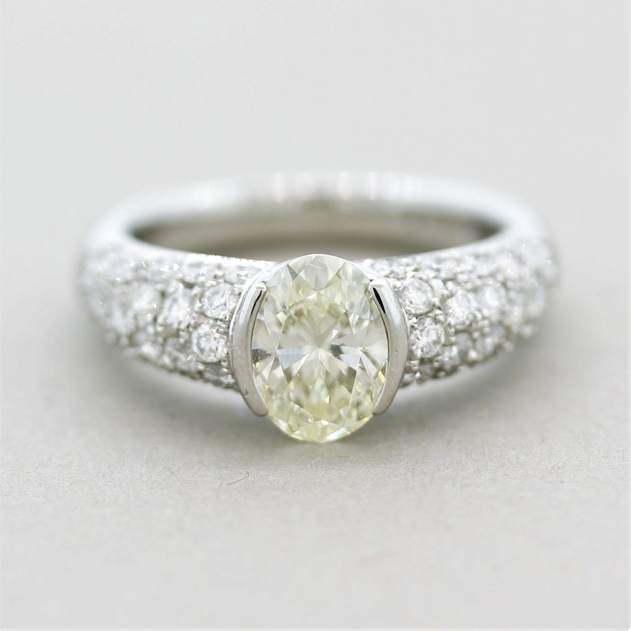 A lovely diamond ring featuring a 1.35 carat fancy light yellow oval shape diamond! It has excellent clarity, VS1, and a soft glowing yellow color. It is accented by 0.91 carats of white round brilliant-cut diamonds which are pave-set on the