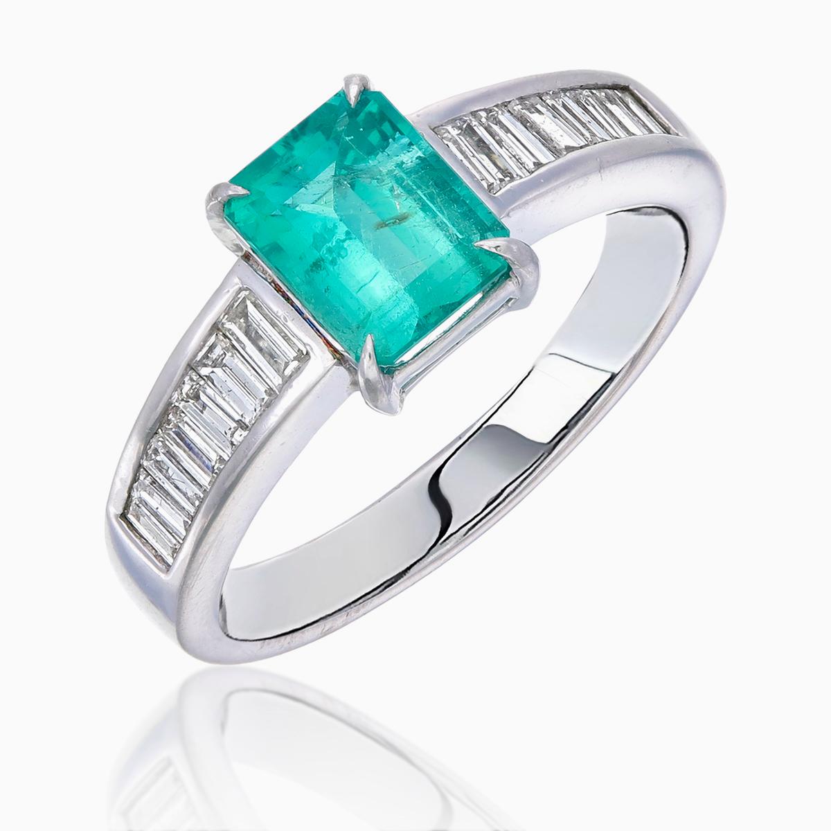 Im Mittelpunkt dieses Rings steht ein 1,35-karätiger Smaragd, der grüne Farbtöne ausstrahlt. Der Smaragd ist von 0,50 Karat Diamanten umgeben, die einen Kontrast bilden, der die natürliche Schönheit des Edelsteins hervorhebt. 

Dieser Ring aus