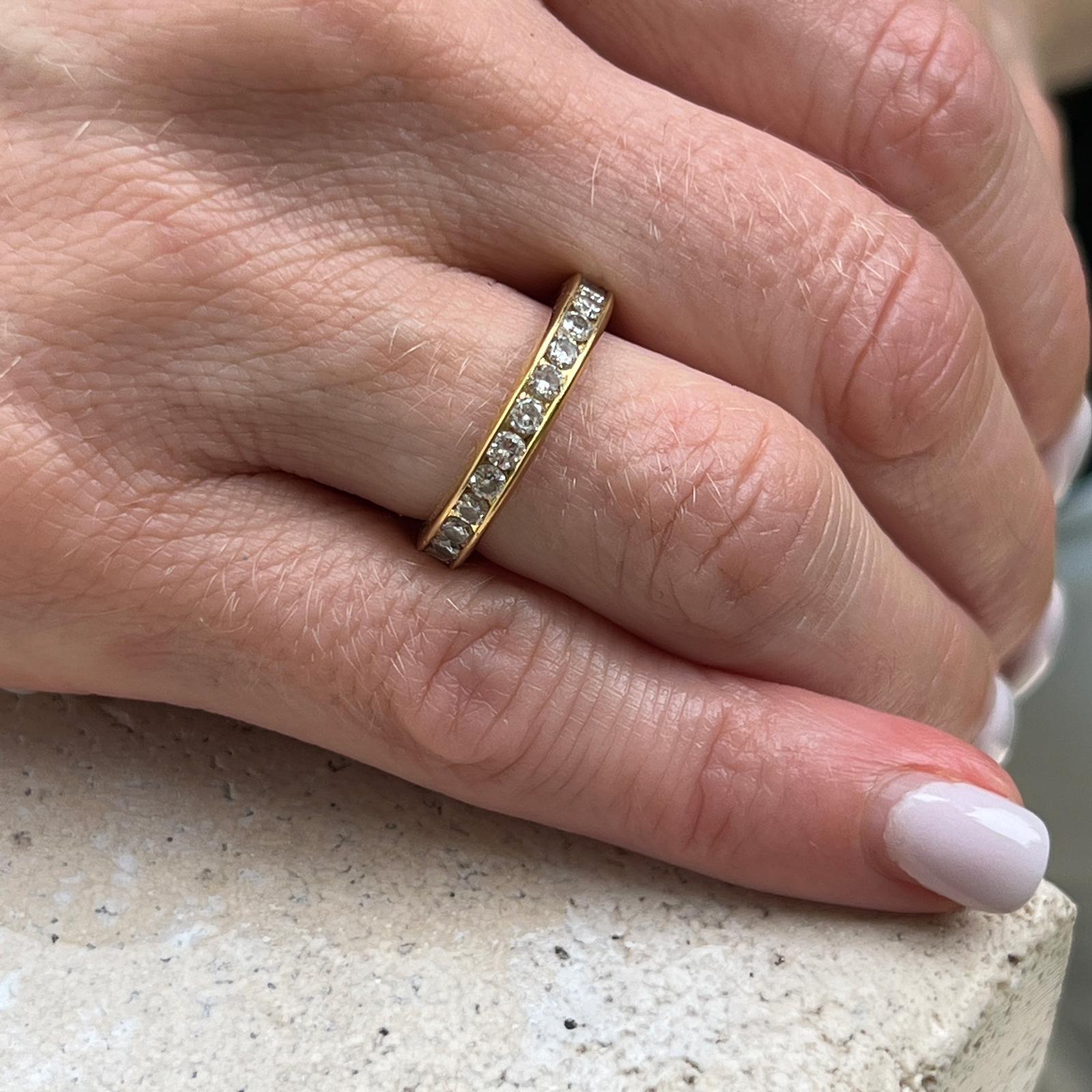 Diamond eternity band crafted in 18 karat yellow gold. The channel set diamonds weigh approximately 1.35 carat total weight and are graded H-I color and SI clarity. The band measures 3.5mm in width and is size 6. 