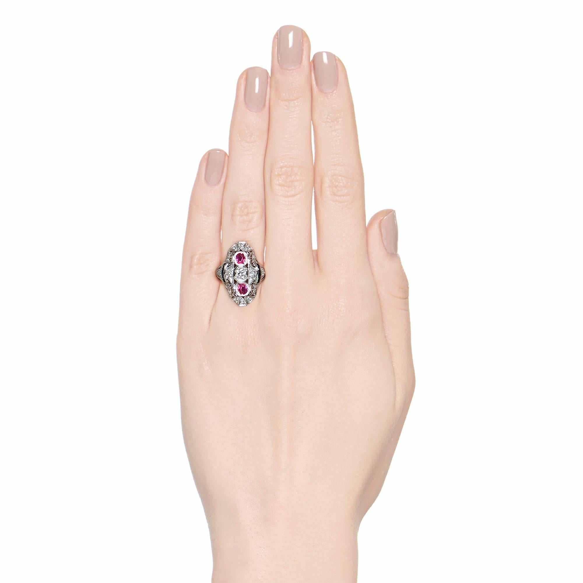 What a statement ring this is!

A trio of rubies and diamonds are bezel set in a vertical orientation, and accented by some intricate filigree work, accented by old cut melee diamonds.

Adorable swirl motif design details add some lightness and